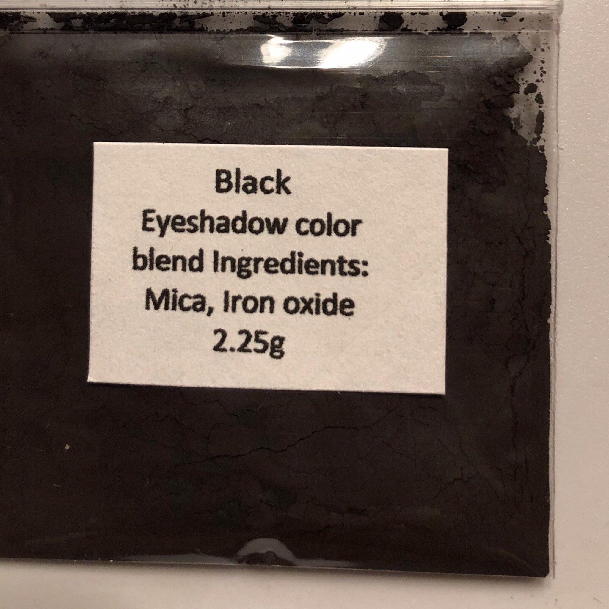 Hand applying soft taupe mineral eyeshadow to eyelid with fluffy brush for natural daytime look