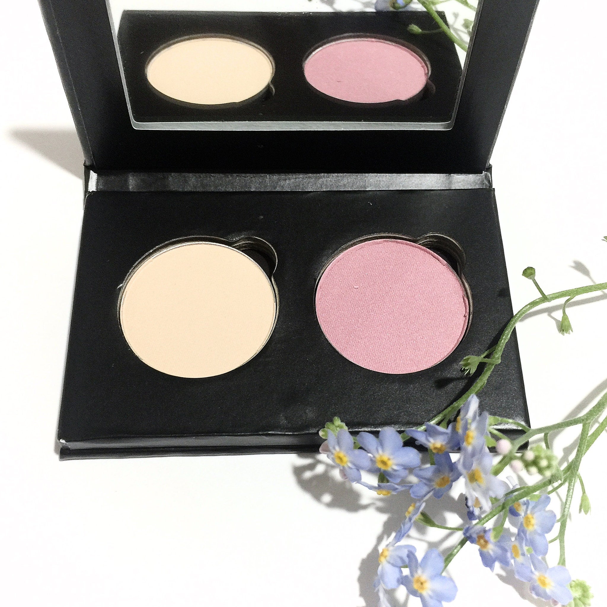 Compact eyeshadow duo with soft pink and creamy vanilla shades in matte finish, housed in a sleek black case