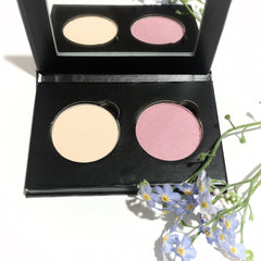 Compact eyeshadow duo with soft pink and creamy vanilla shades in matte finish, housed in a sleek black case