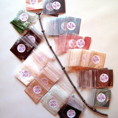 Close-up of six small resealable bags containing mineral eye shadow powders in various matte and shimmer shades
