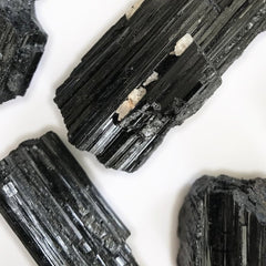 Black tourmaline crystals with white inclusions, rough texture, on white background