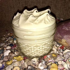 Healing cream in a glass jar with diamond pattern, cream-colored balm, and seashells around it