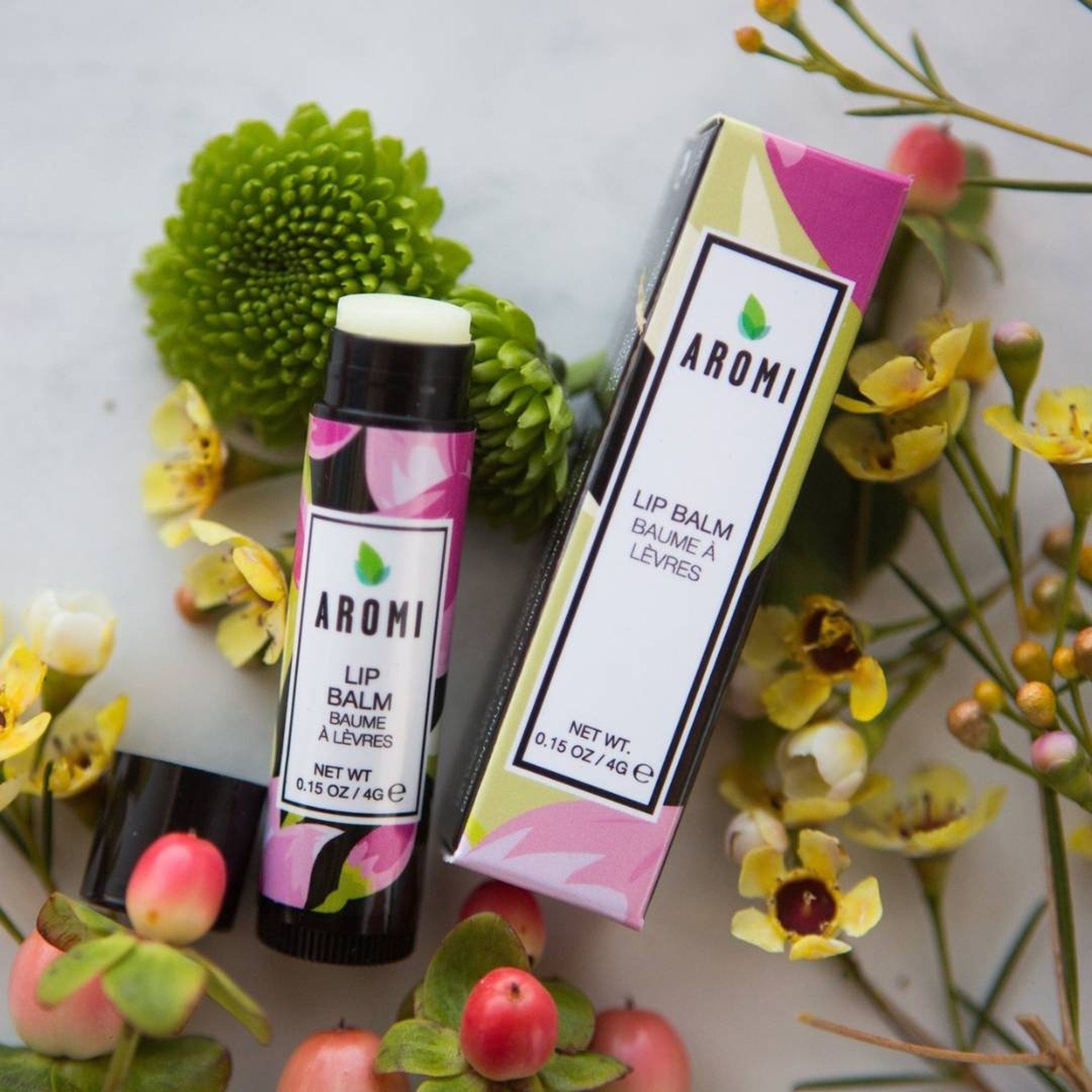 Lip balm tube and box with floral pattern, Aromi brand, surrounded by flowers