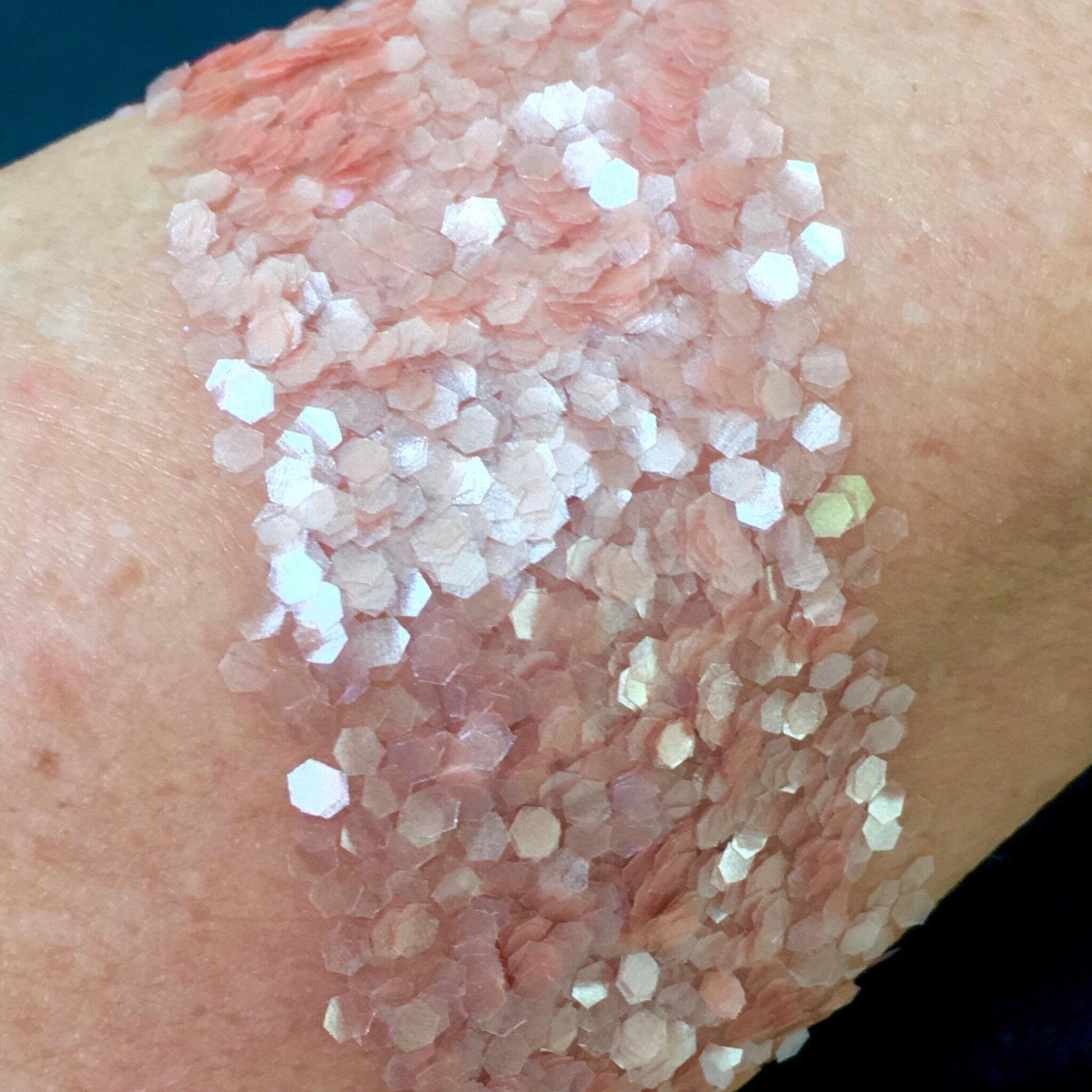 Glitter flakes, pink and white hexagonal flakes on skin, cosmetic application