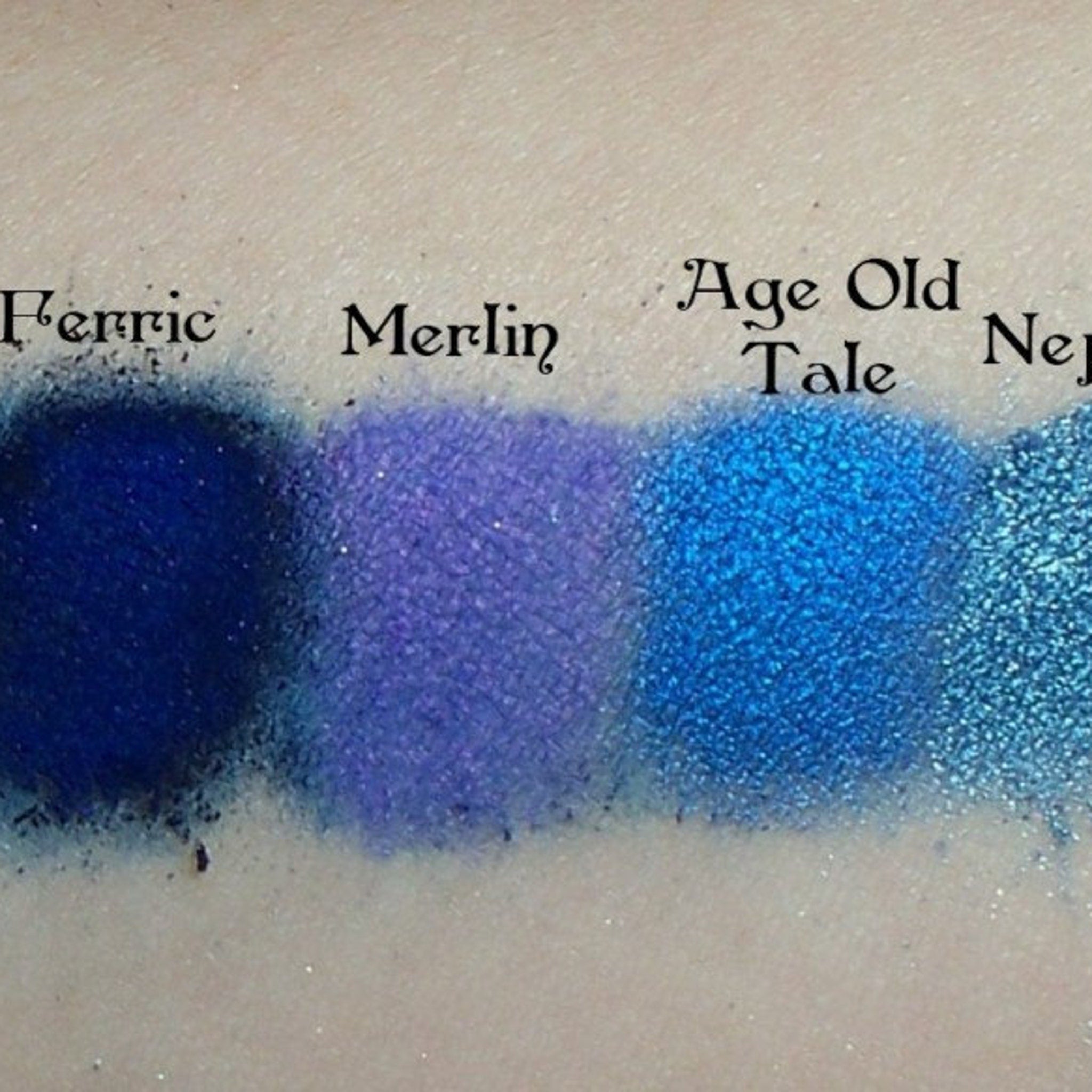 Eyeshadow swatches with blue and purple shades, Age Old Tale brand name visible