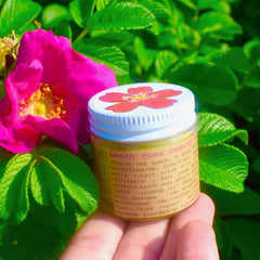 Pink glass jar of Beach Rose Nourishing Beauty Balm with gold lid and minimalist typography