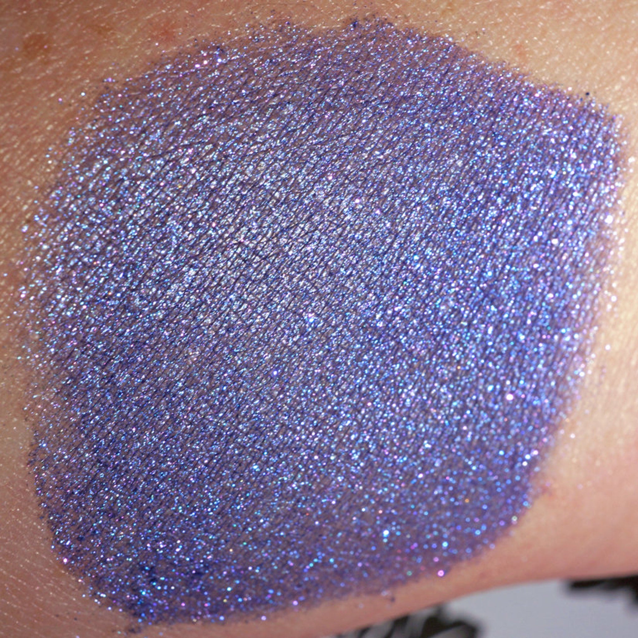 Side view of loose pigment jar showing African Violet metallic indigo eyeshadow with shifting glitter particles