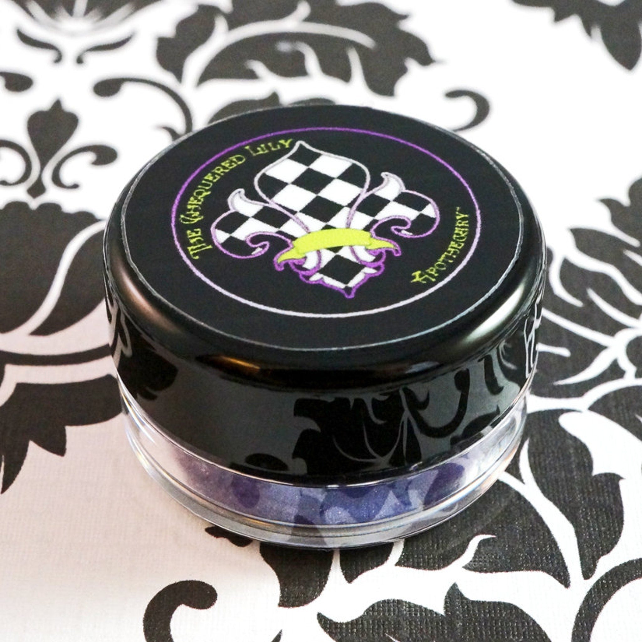 Side view of loose African Violet eye shadow pigment showing shifting indigo glitter in dark purple mineral powder