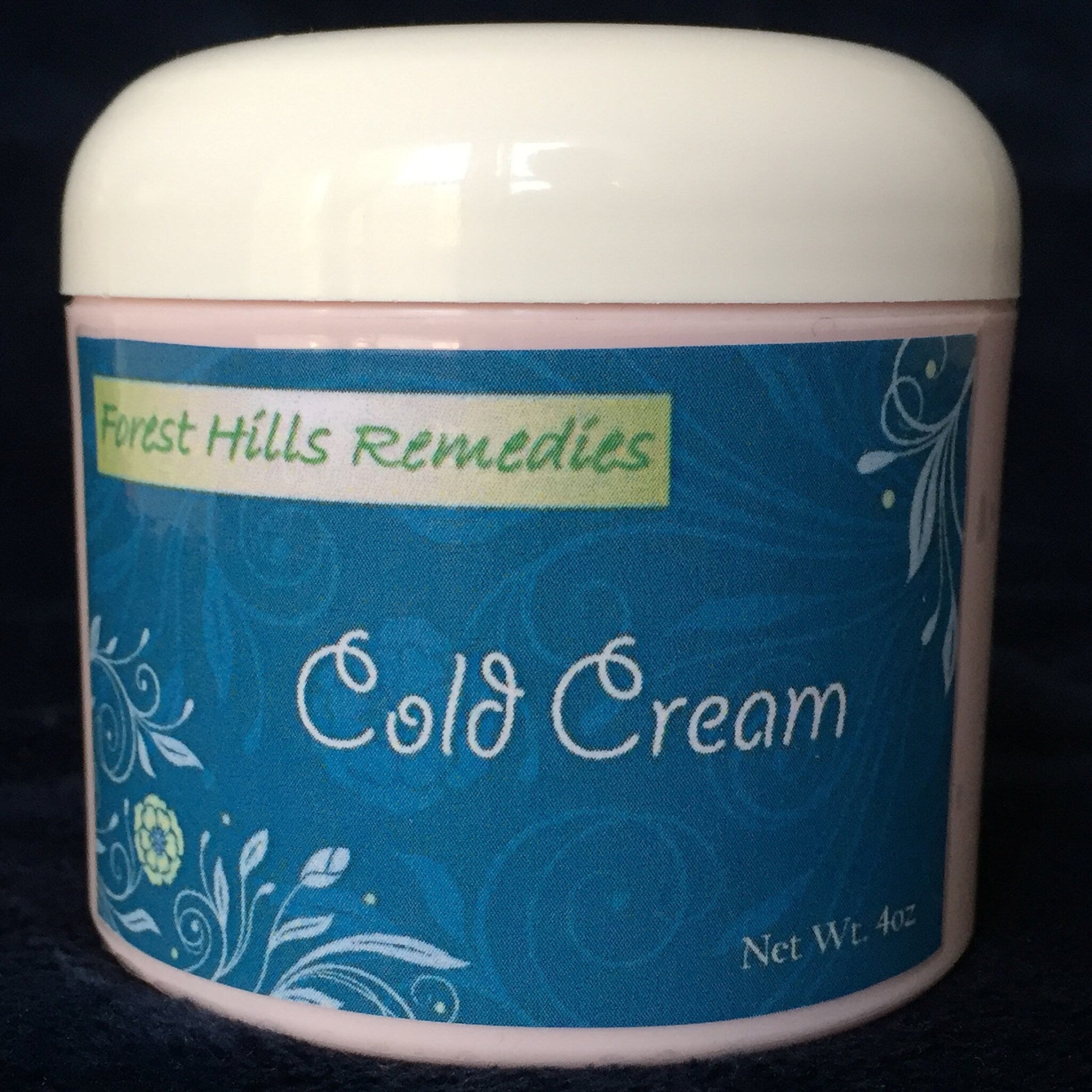 Cold cream jar with white lid, pink base, and blue label with Forest Hills Remedies text and floral pattern
