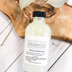 Makeup remover bottle with black cap and white label, on wood surface, Butter Me Up Organics brand