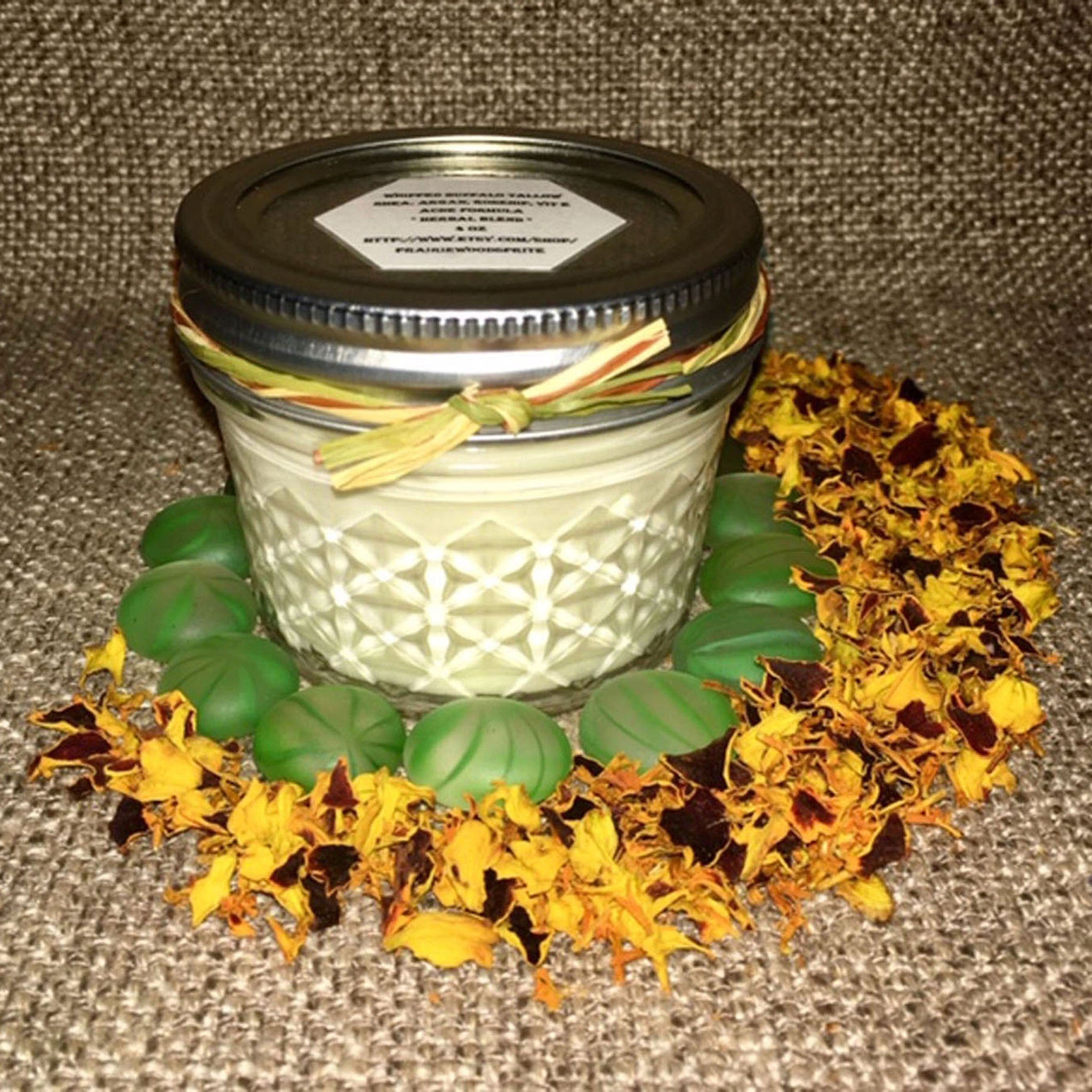 Jar candle with silver lid, clear glass, and yellow floral accents around base