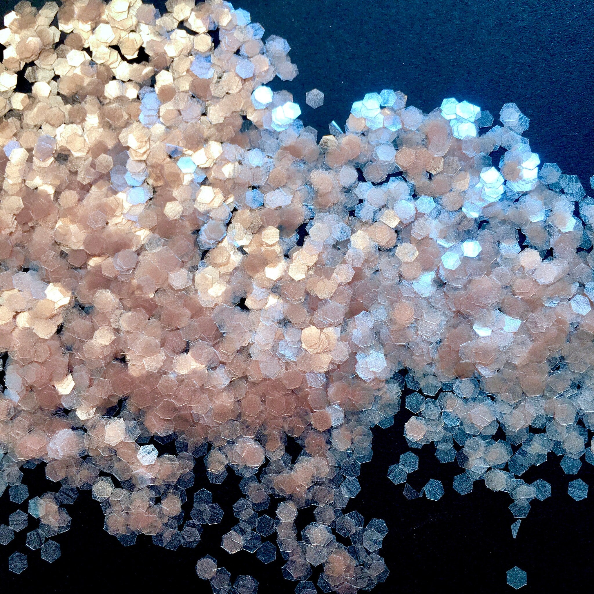 Body glitter, pink and silver hexagonal glitter, scattered on black surface