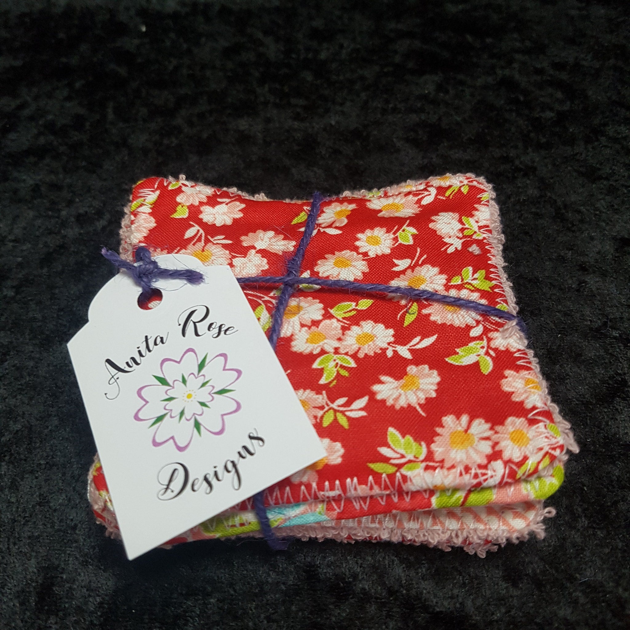 Reusable face wipes, red floral print, with Anita Rose Designs tag, tied with purple twine