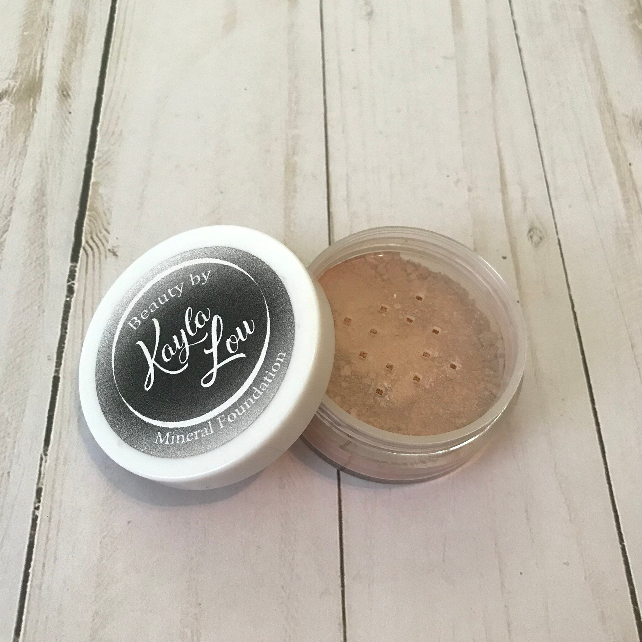 Mineral foundation powder in clear plastic jar with white lid, Beauty by Kayla Lou branding