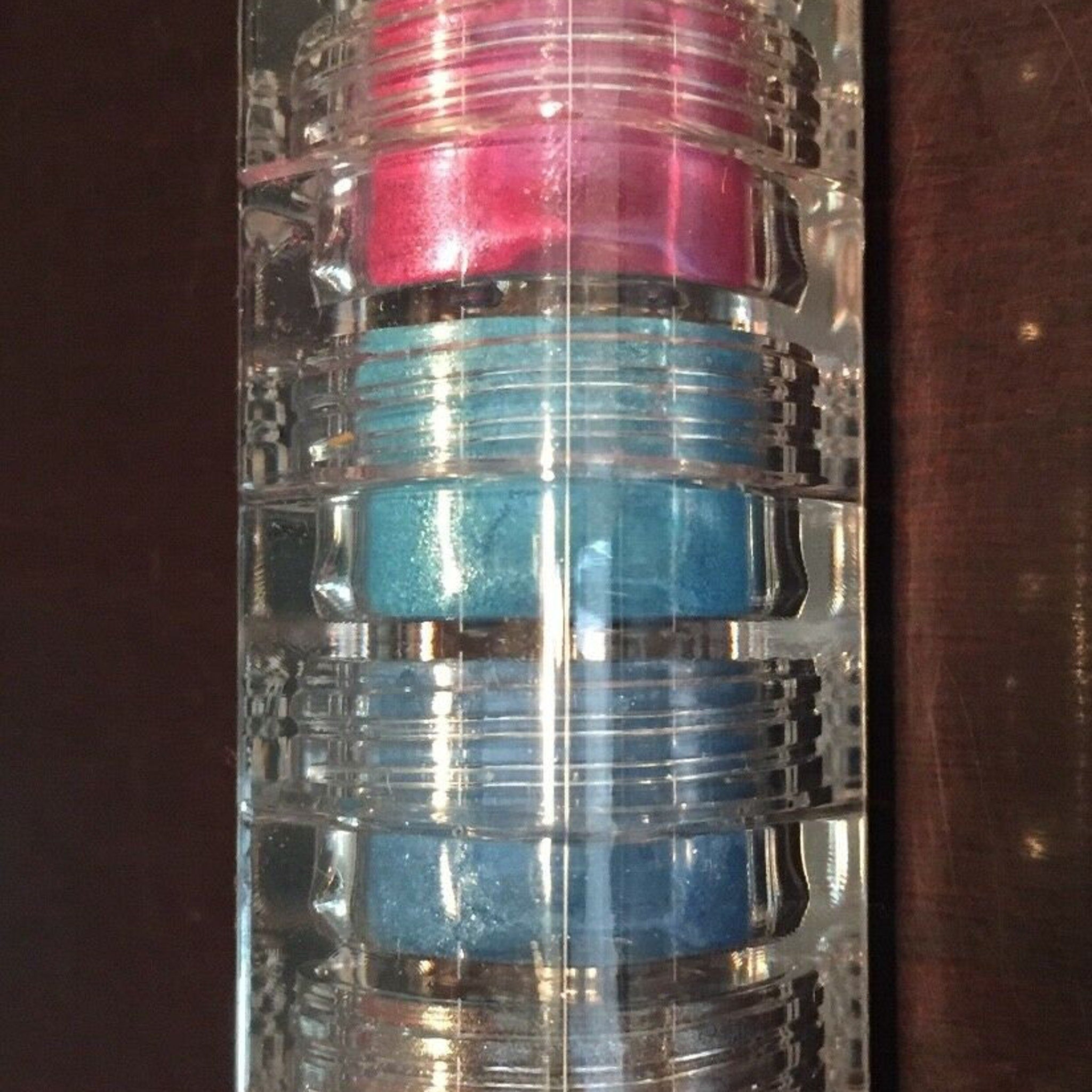 Mineral eyeshadow stack with pink, blue, and clear plastic containers, True Colors USA brand
