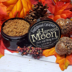 Sugar scrub in black jar with brown granules, Harvest Moon label, and fall foliage