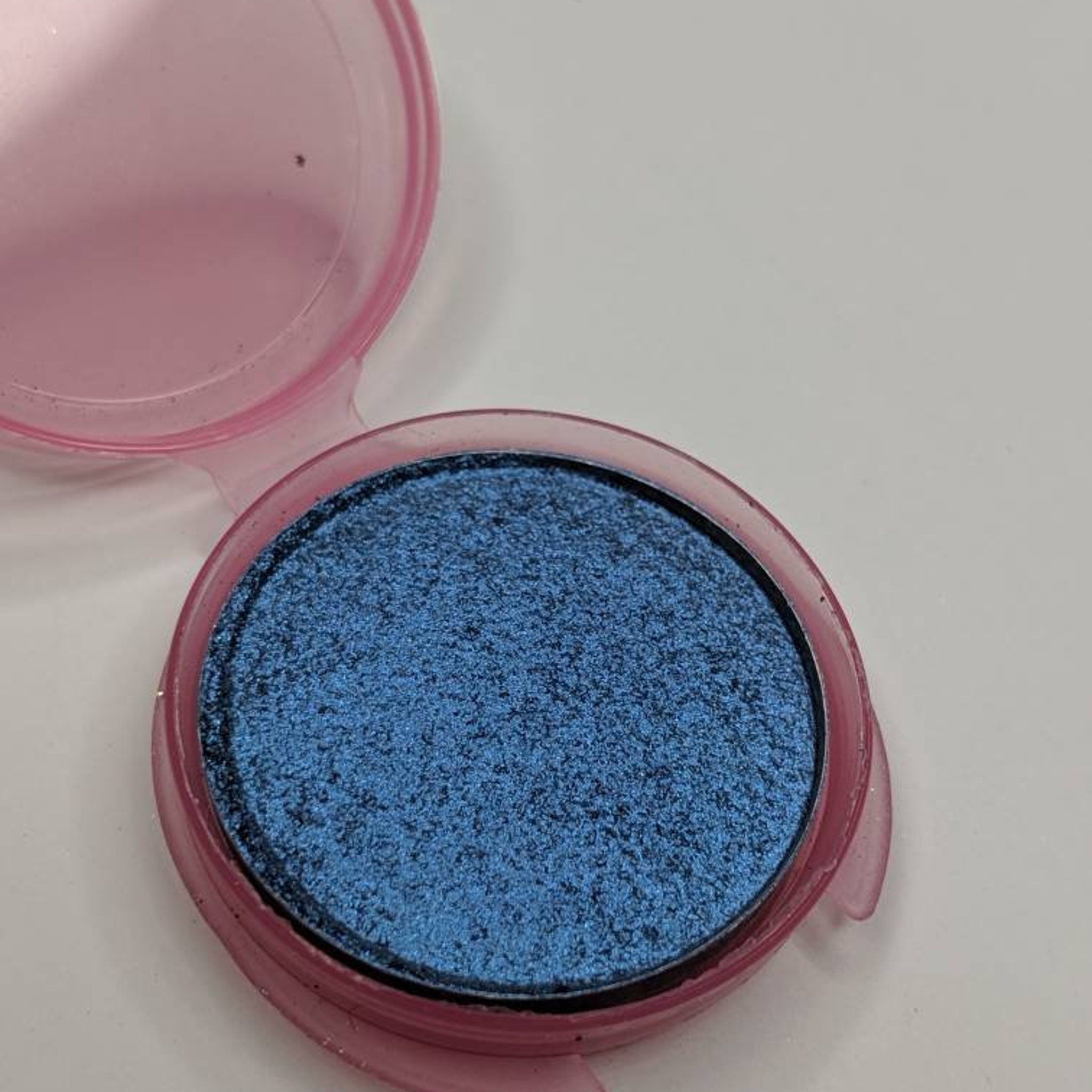 Close-up of vegan sapphire blue pressed eyeshadow with smooth, pigmented finish in compact case