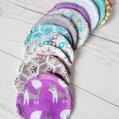 Reusable nursing pads with various patterns, colors, and white stitching around the edges.