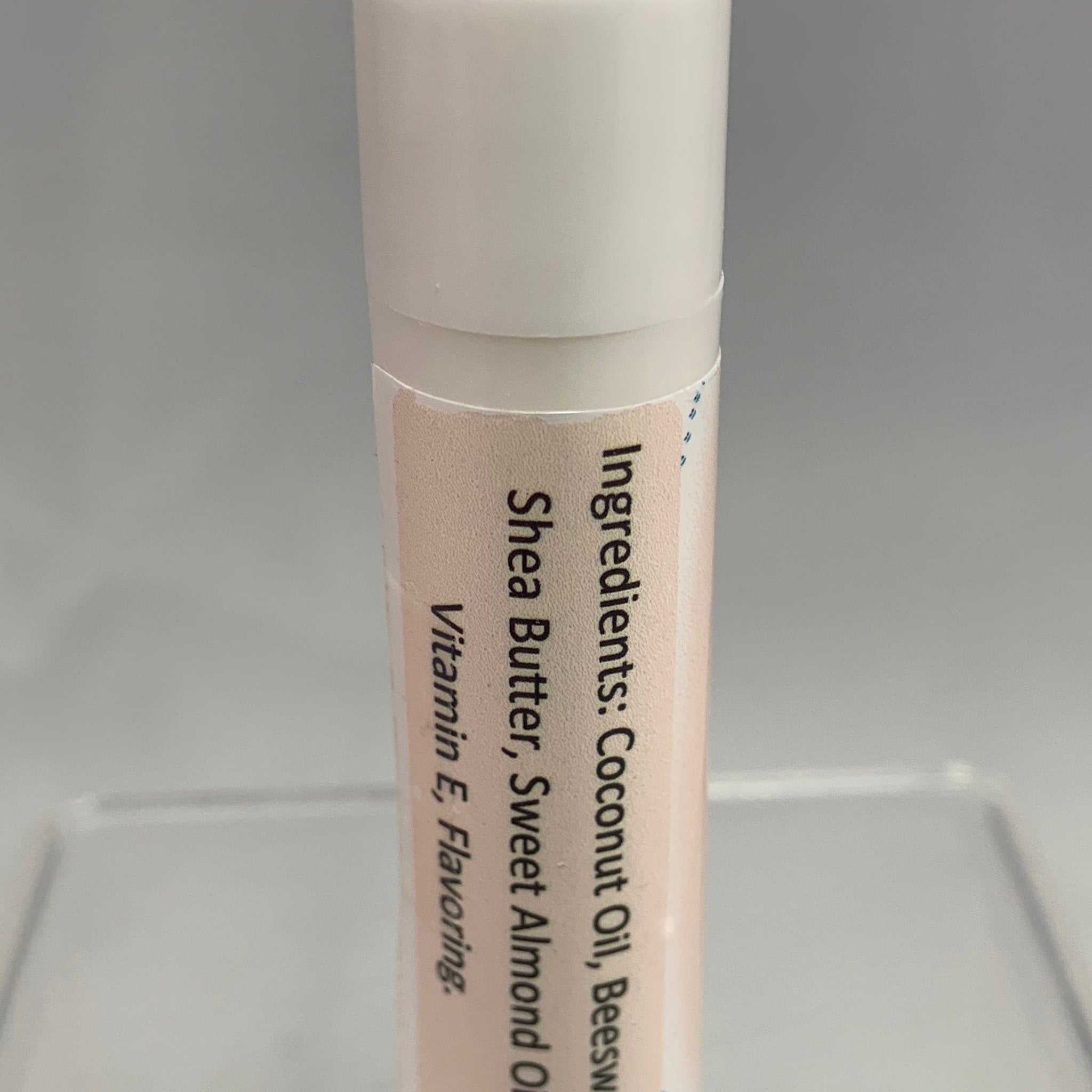 Lip balm tube with white and peach colors, ingredients list visible on label
