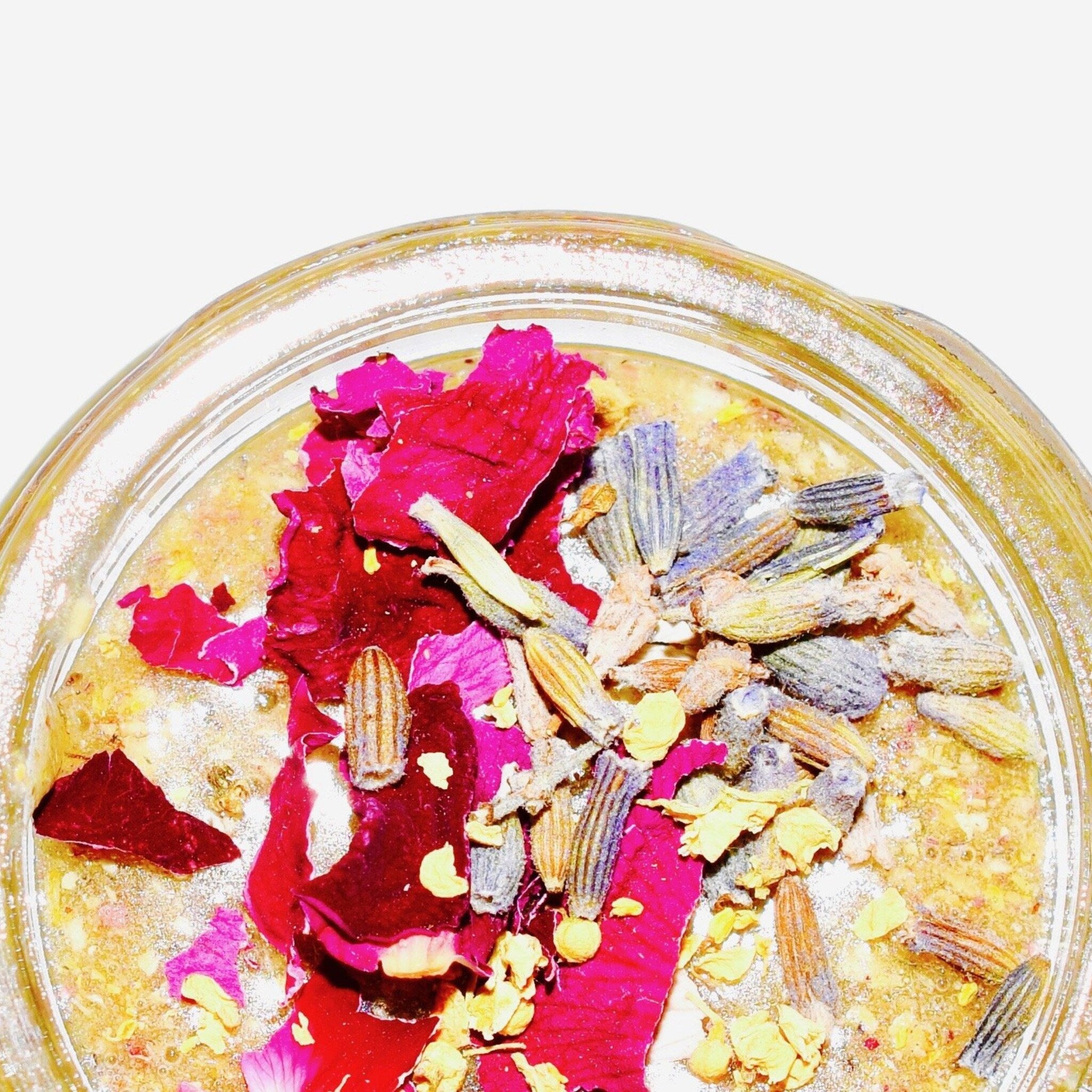 Dried flower arrangement with red, purple, and yellow petals in a clear glass container