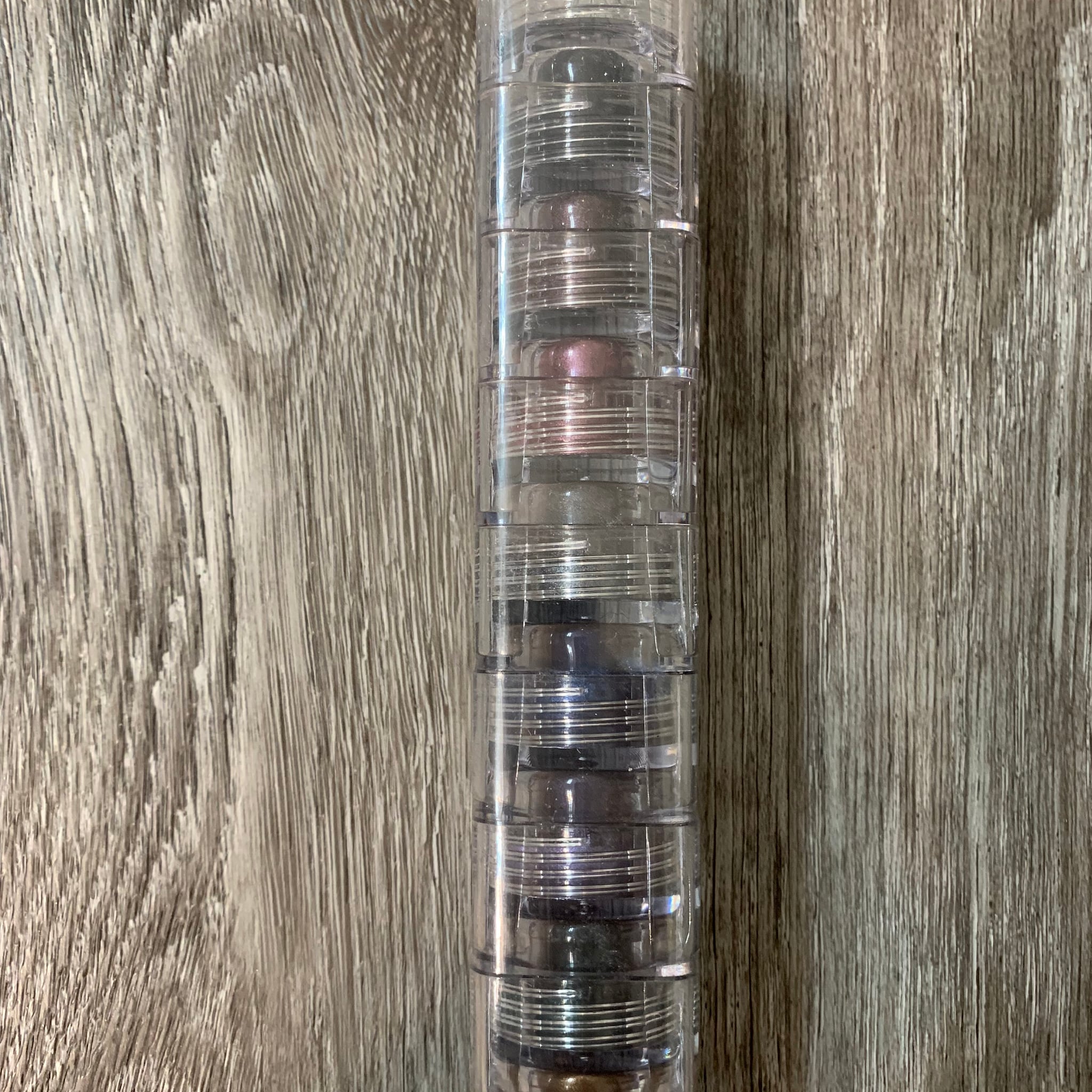 Mineral eyeshadow stack with clear plastic container, multiple colors, stacked vertically