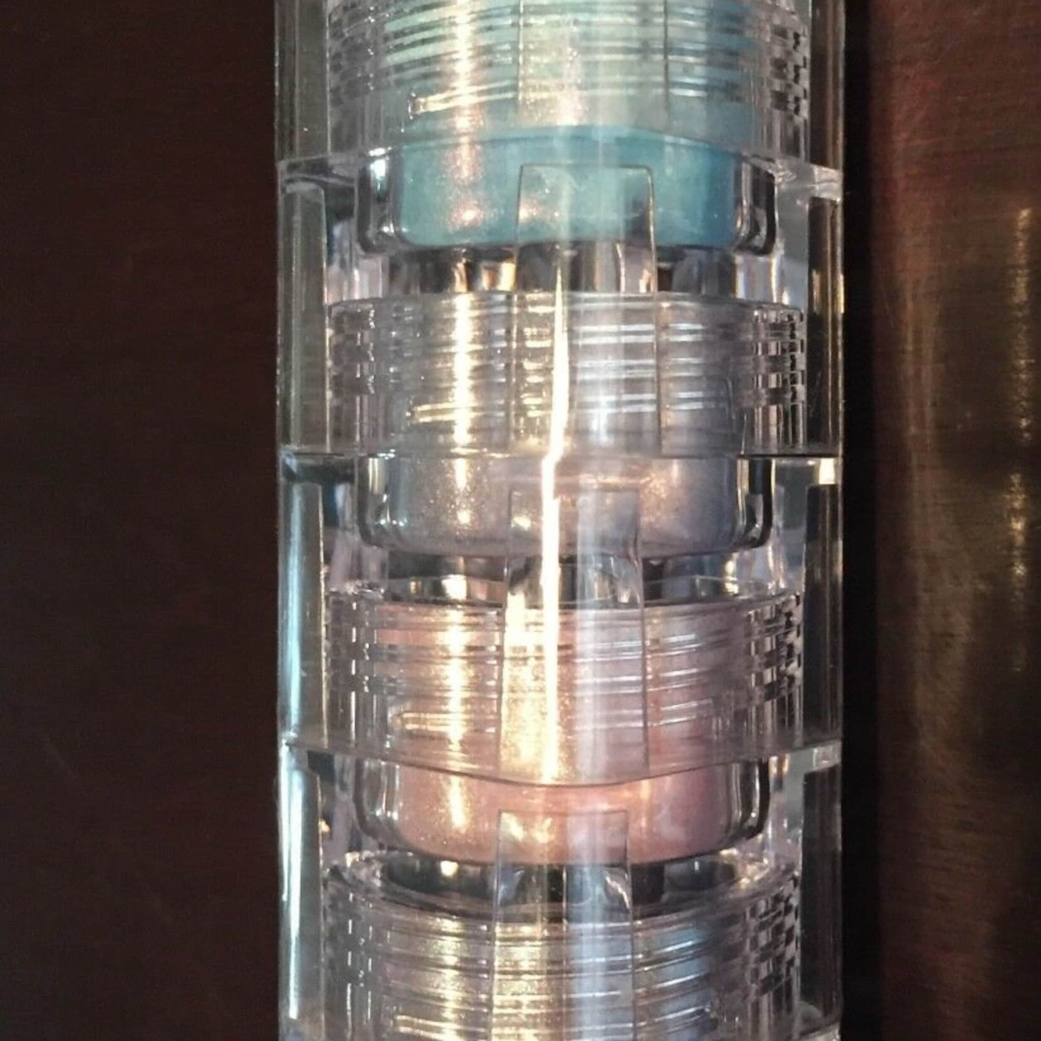 Mineral eyeshadow stack with blue, silver, and pink shades in clear plastic container