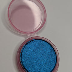 Close-up of vibrant teal blue pressed eyeshadow with smooth matte finish in compact case