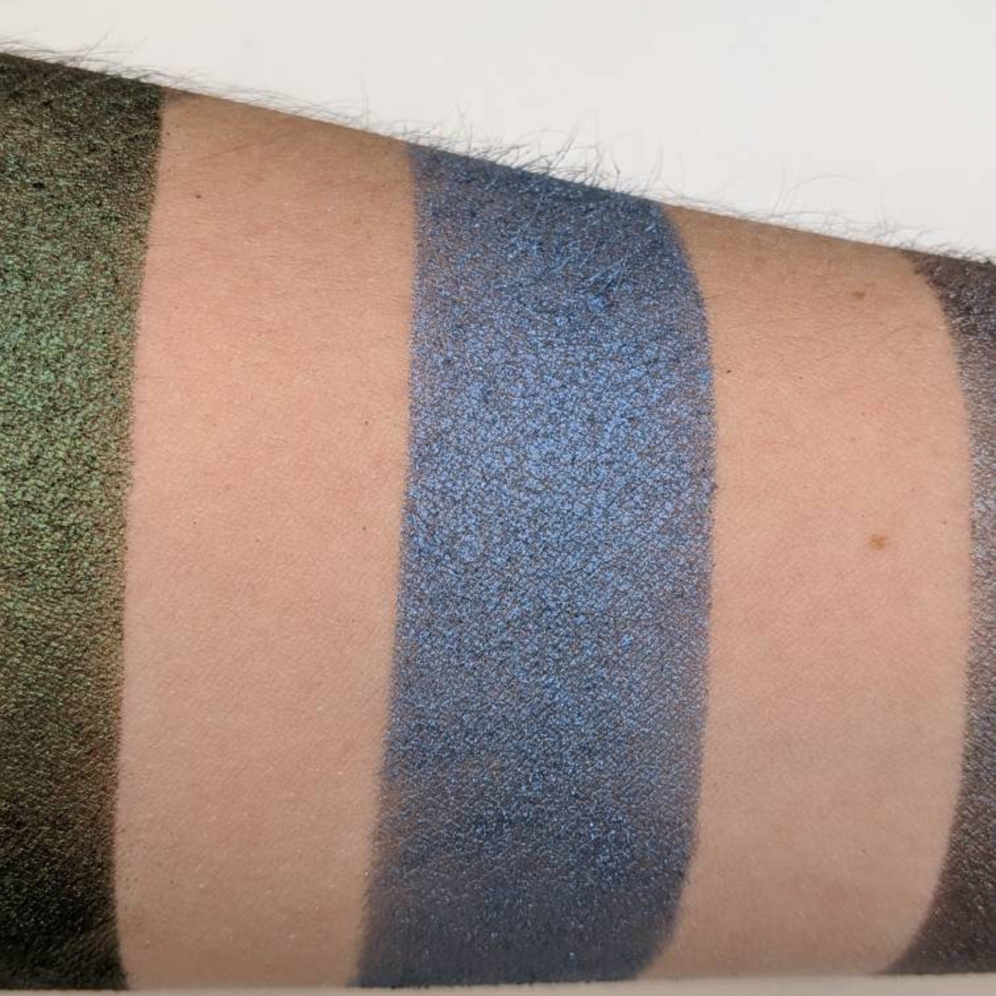 Side angle view of vegan sapphire blue pressed eyeshadow in compact palette showing rich pigment texture