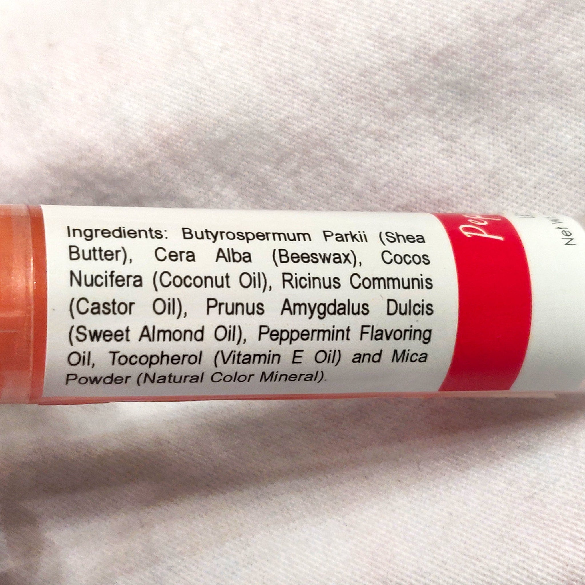Lip balm tube with red stripe and ingredient list on white background, Amiyah Natural Products