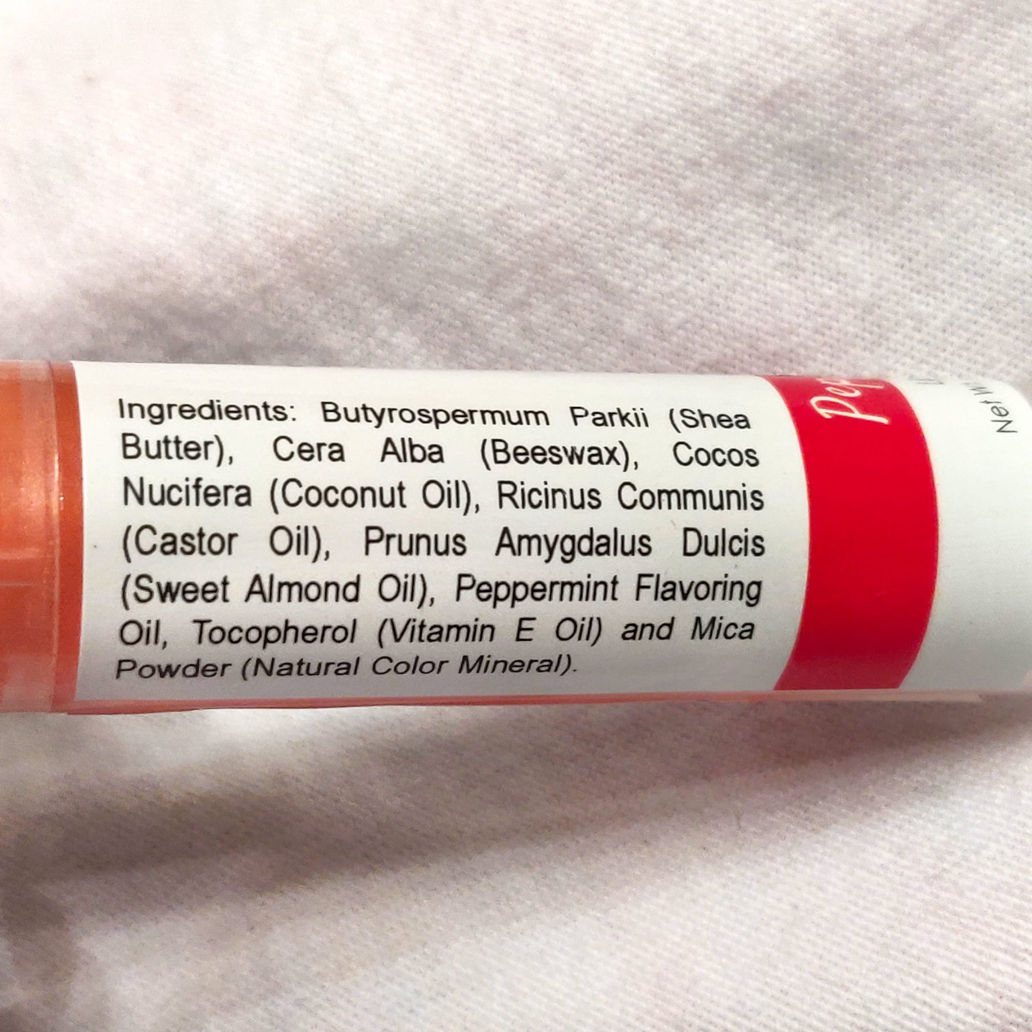 Lip balm tube with red and white label, ingredients list visible, Amiyah Natural Products text