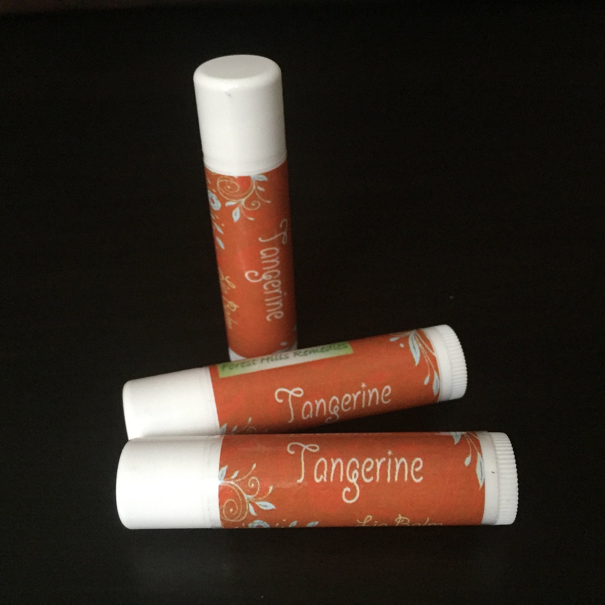 Lip balm tubes with orange and white labels, floral pattern, and "Tangerine" text