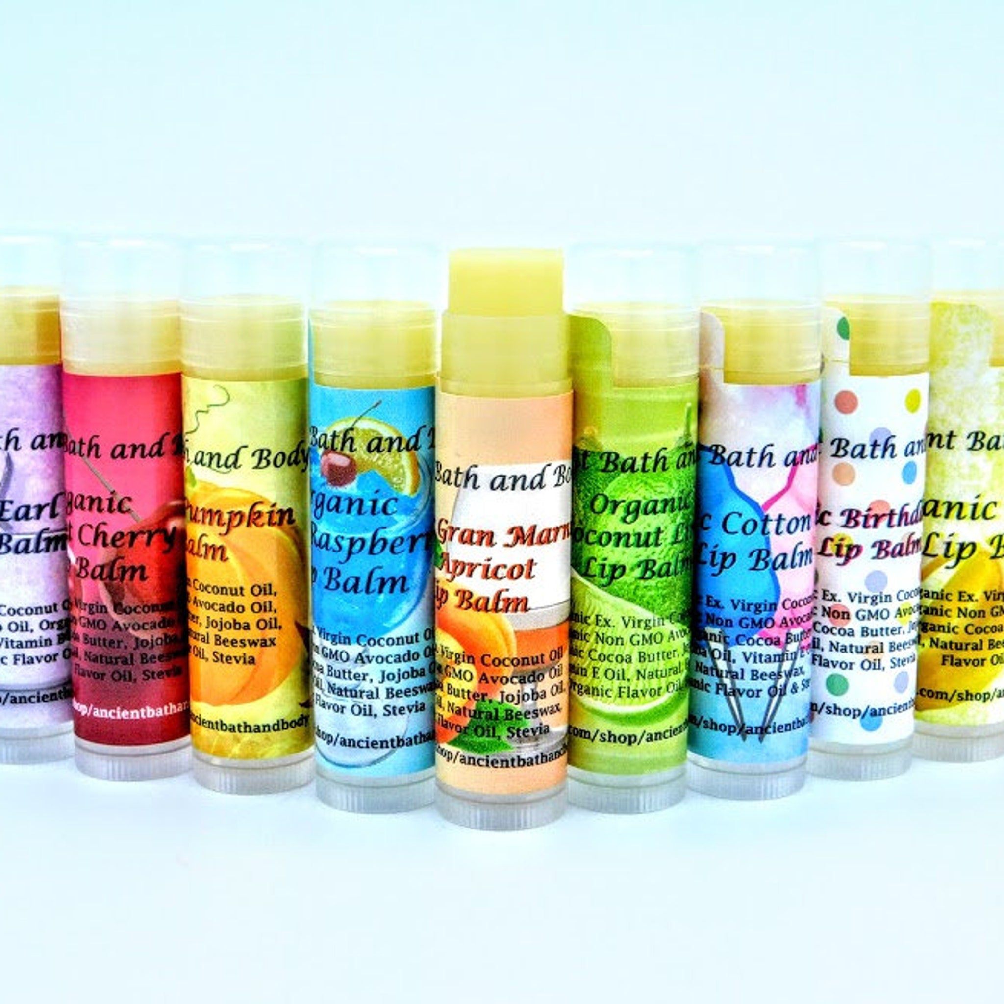 Lip balm tubes with colorful labels, Ancient Bath and Body branding, and various flavors shown