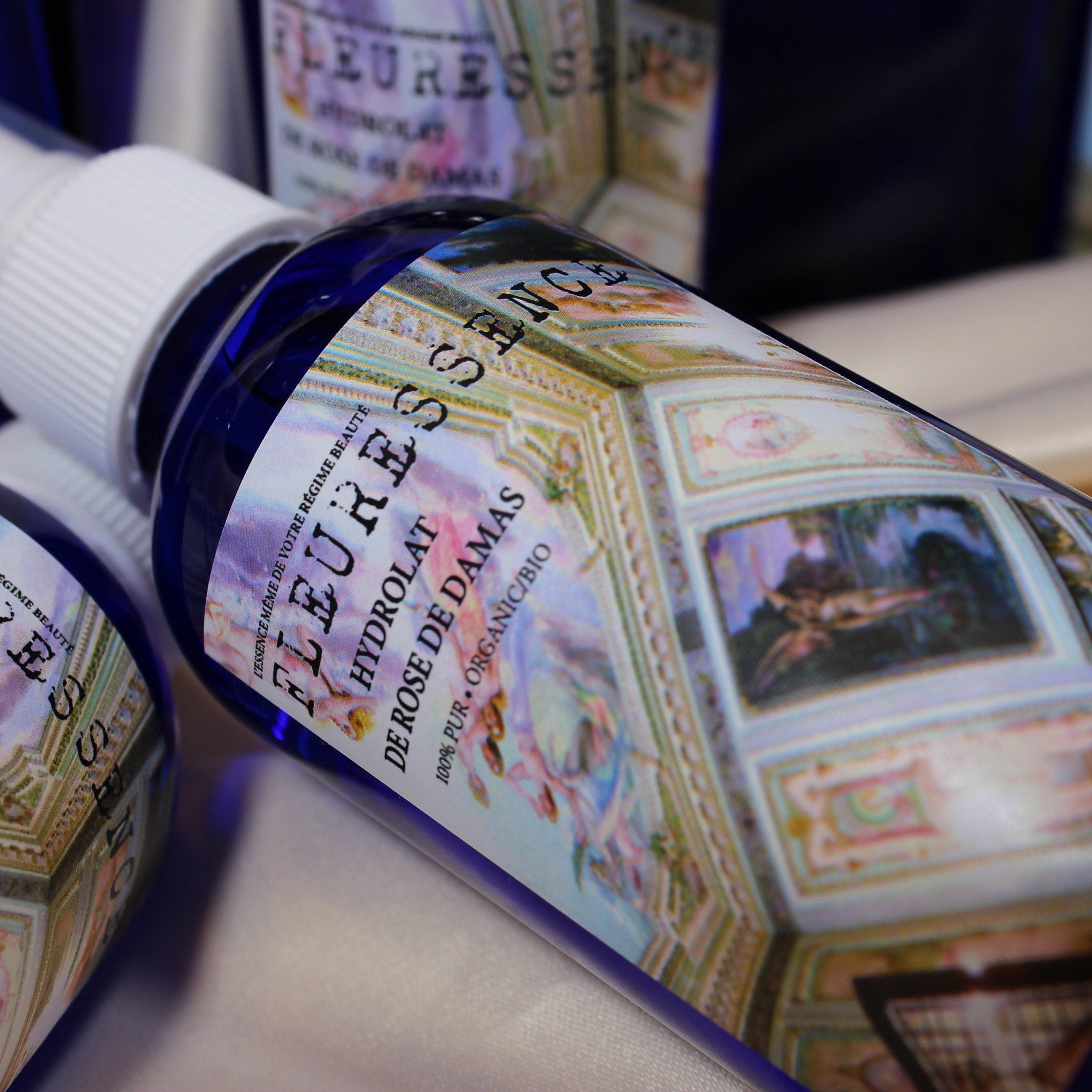 Hydrolat bottle with blue glass, white sprayer, and ornate label with text