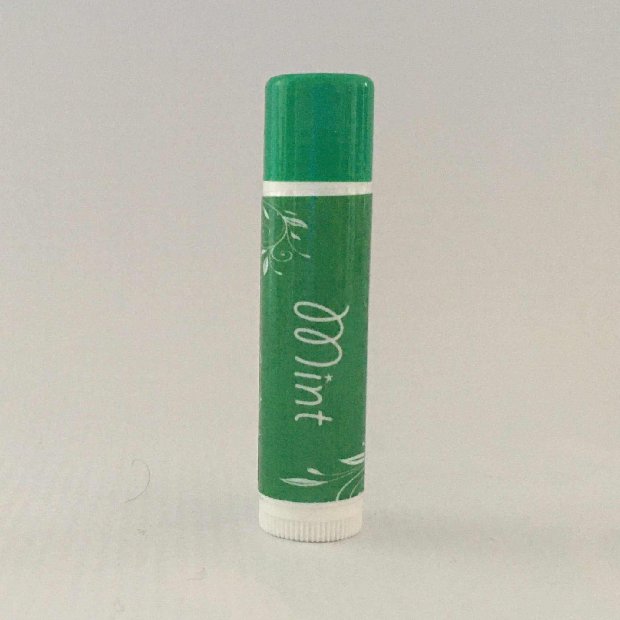 Lip balm tube, green with white "Mint" text and floral design, white base