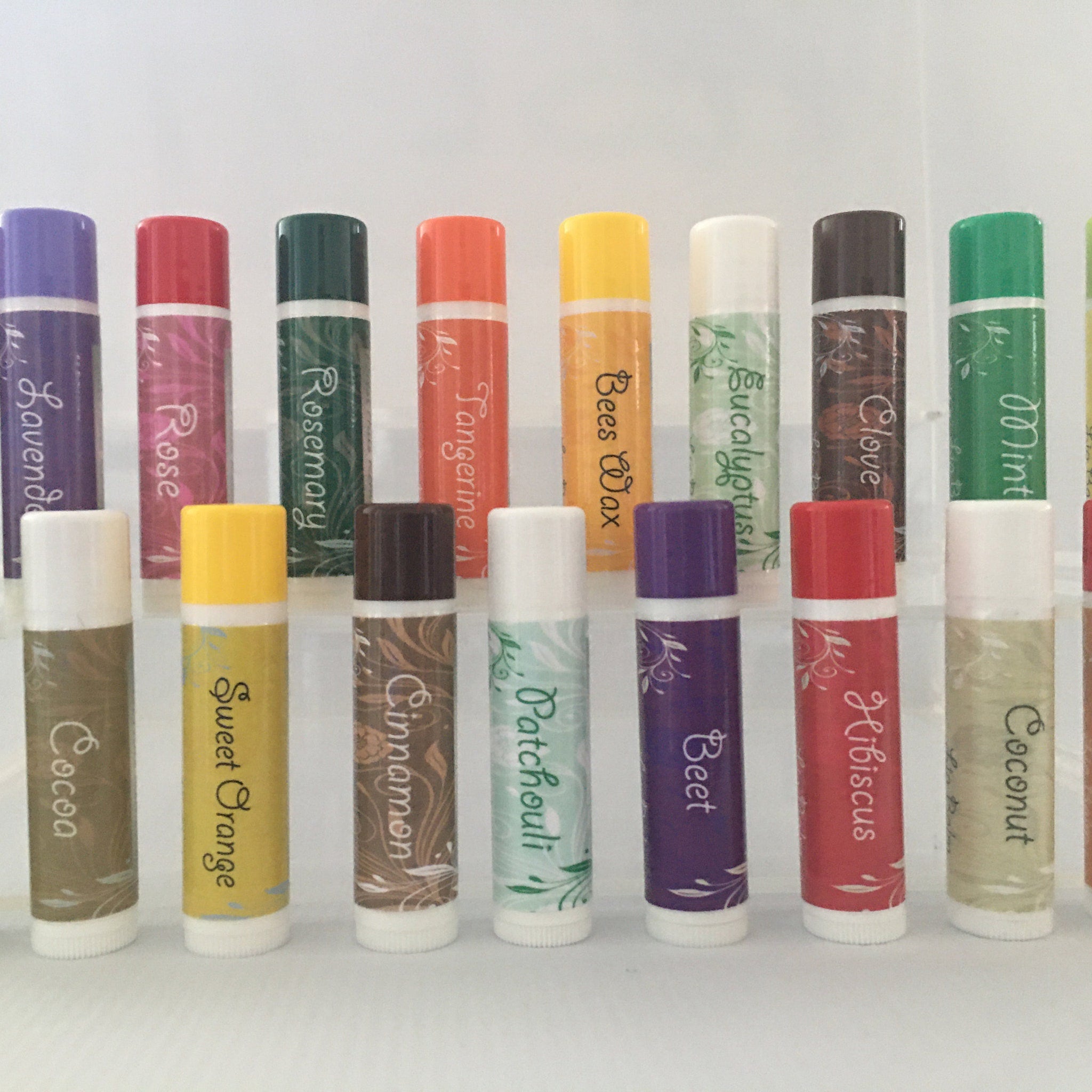 Lip balm tubes in various colors with labels, white caps, and floral design accents