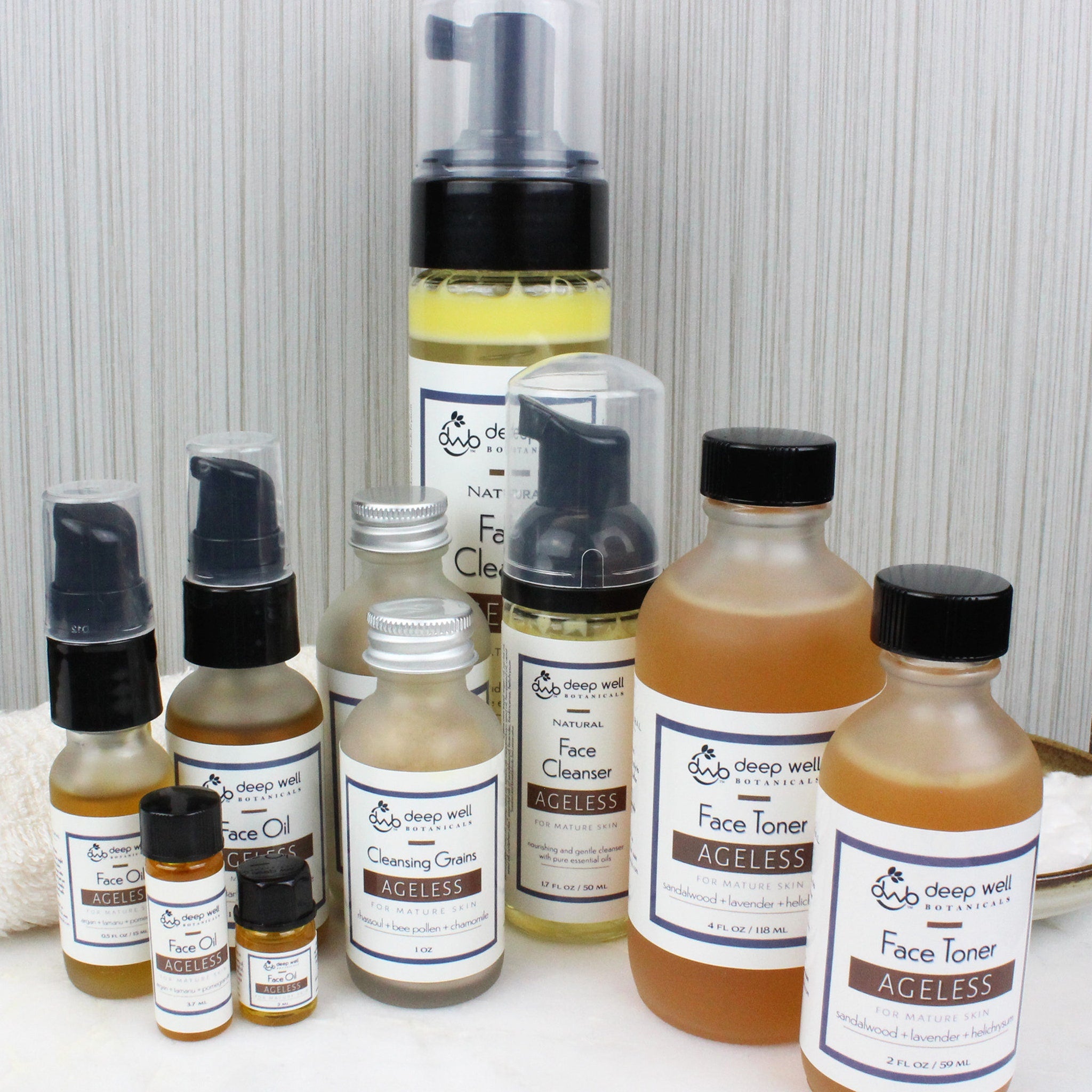 Skincare products assortment with glass bottles, black caps, and white labels of Deep Well Botanicals