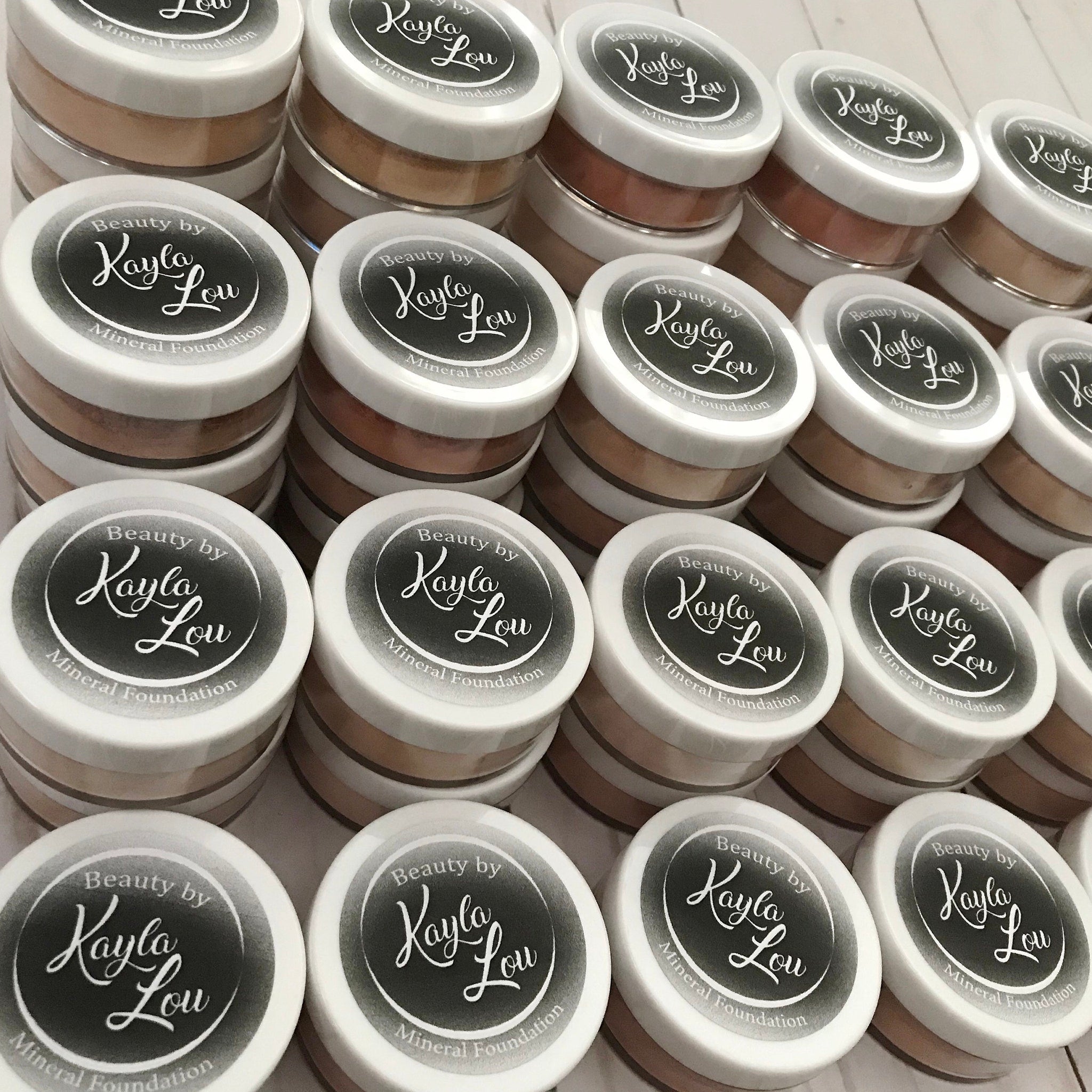 Mineral foundation jars with white lids, brand text, and various shades of powder inside