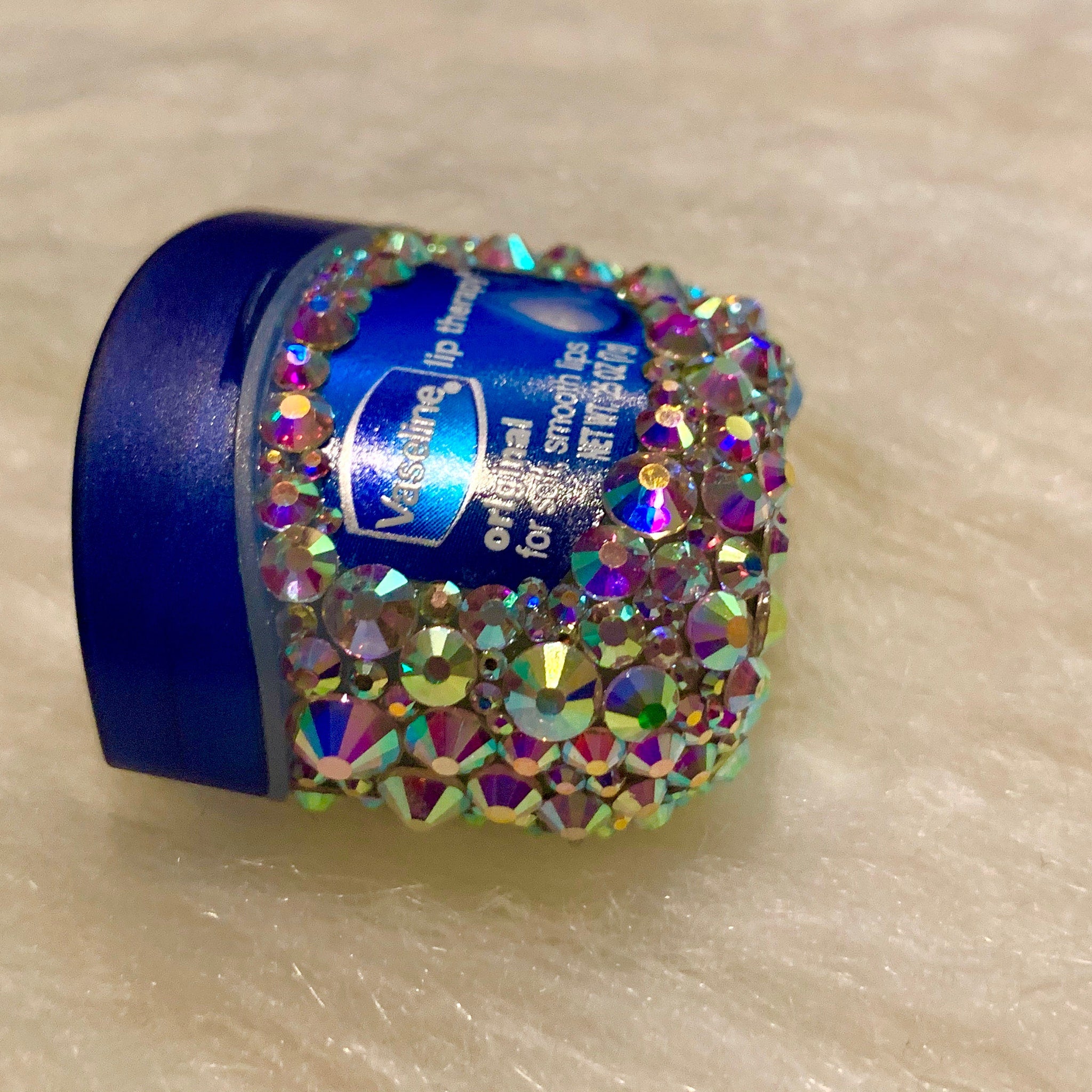 Lip therapy container with blue lid, iridescent rhinestones, and Vaseline branding
