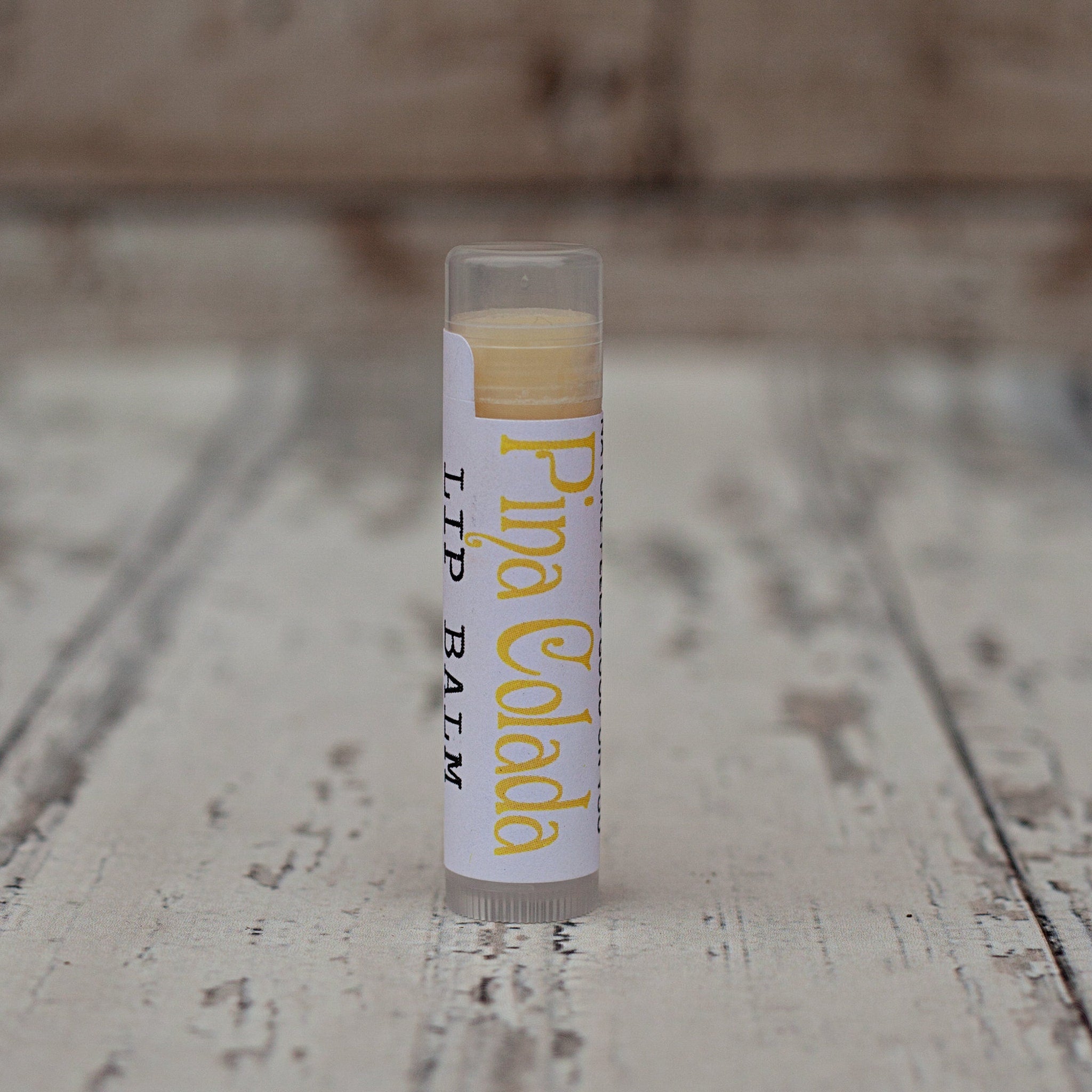 Lip balm tube with white label, yellow text, and clear plastic cap and base