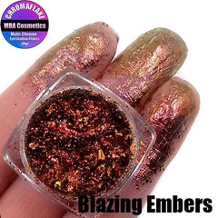 Glass jar of Blazing Embers multichrome eyeshadow flakes shifting between copper, gold, and fiery red tones