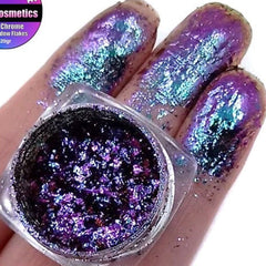 Close-up of Delirious Chromaflake multichrome eye shadow flakes shimmering with shifting rainbow hues in a pot