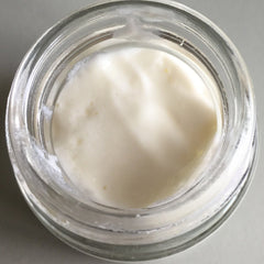 Cream in glass jar with white cream and clear glass rim, angled view