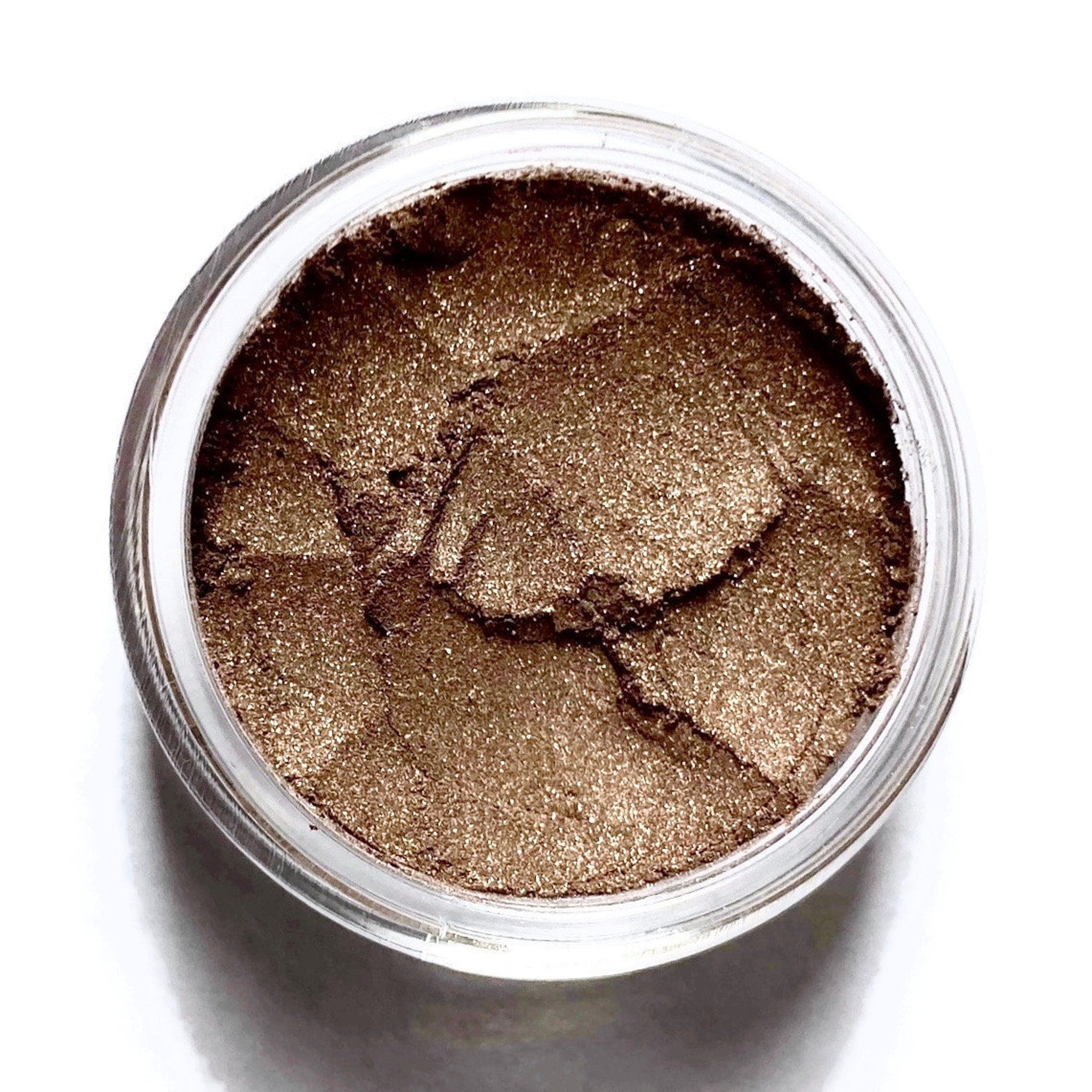 Bronze metallic eyeshadow pan with shimmering brown tones in compact packaging, cruelty-free and vegan.