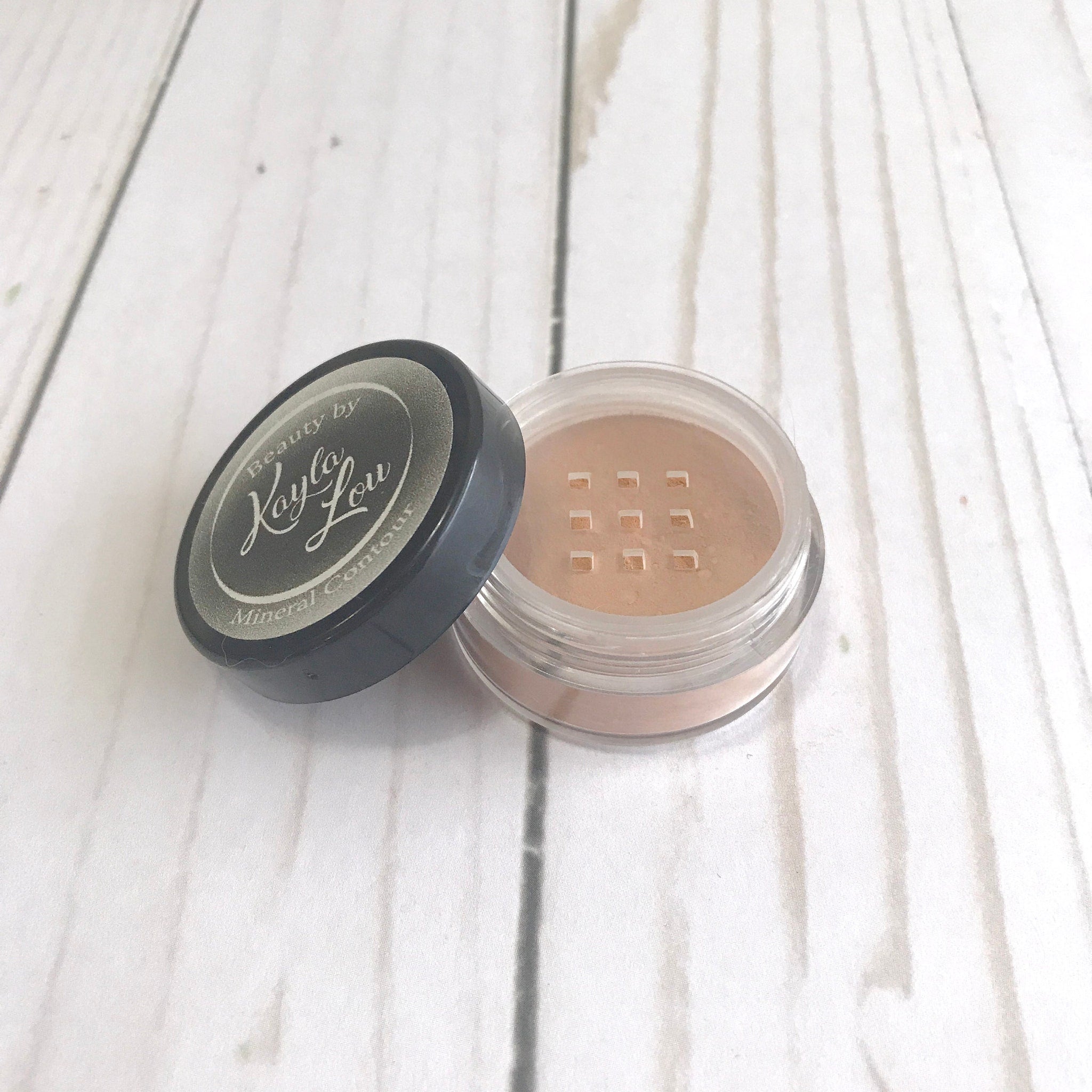 Mineral contour powder with tan color, clear plastic jar, and Beauty by Kayla Lou label