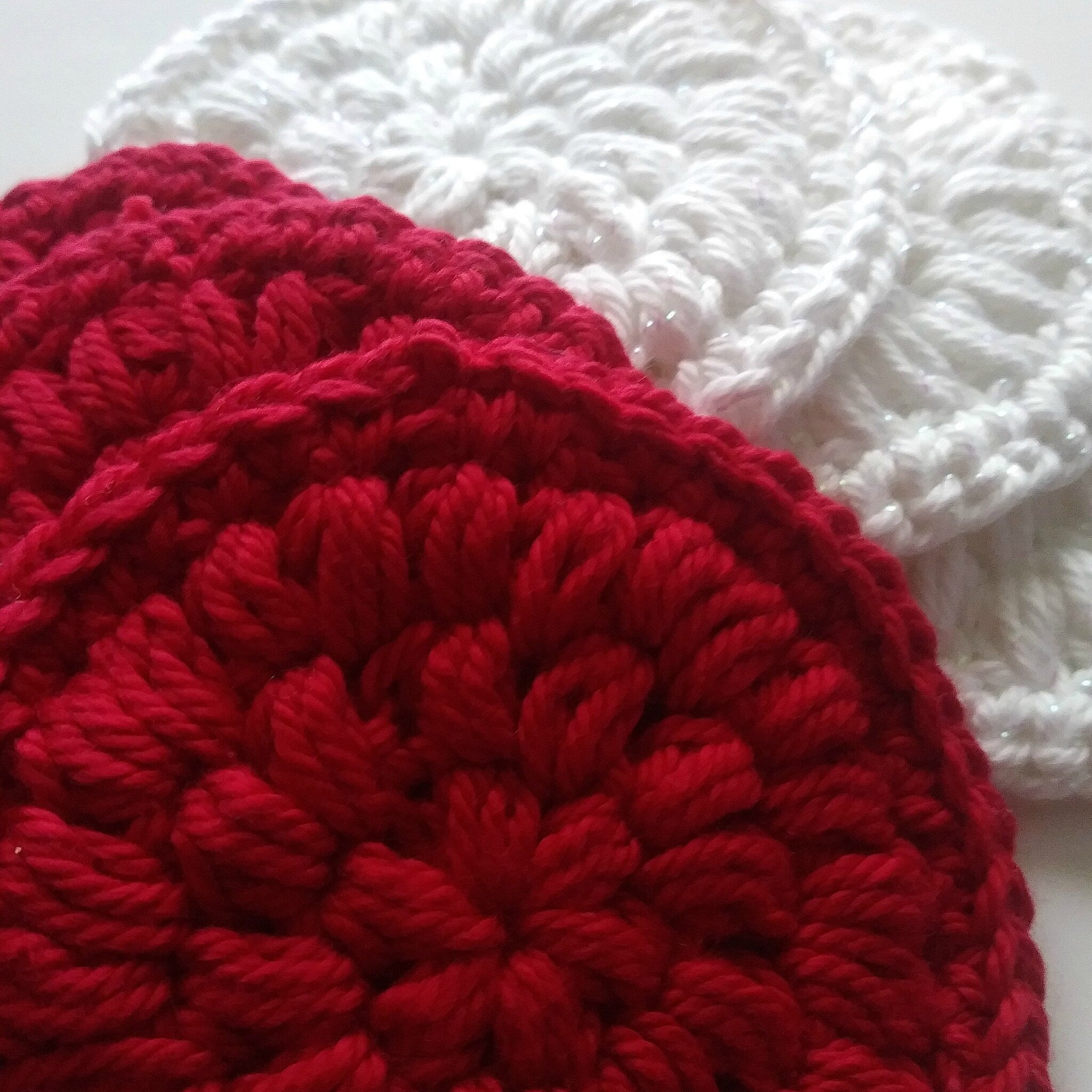 Crochet coasters red and white yarn with textured pattern and round shape