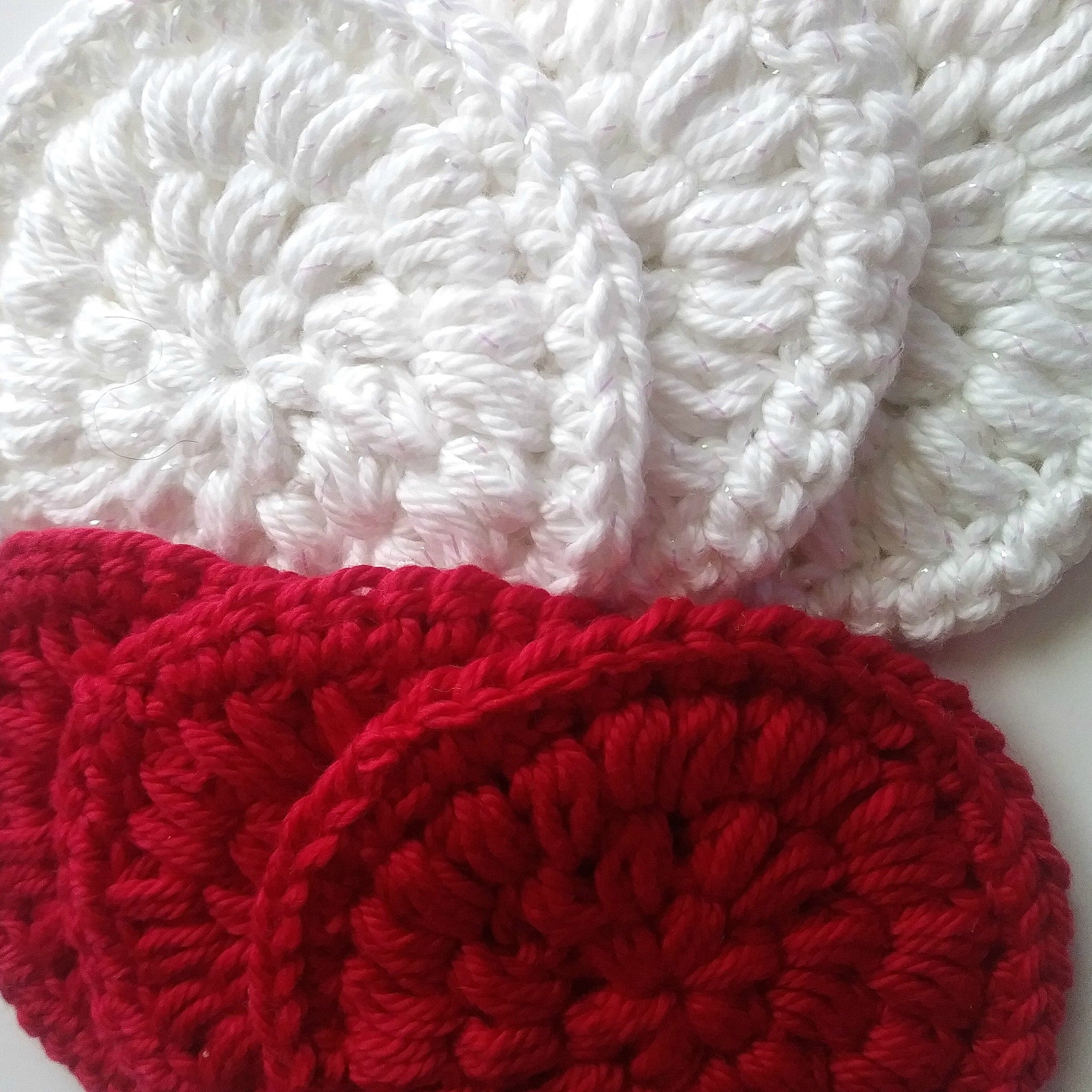 Crochet coasters in white and red, textured yarn, round shape