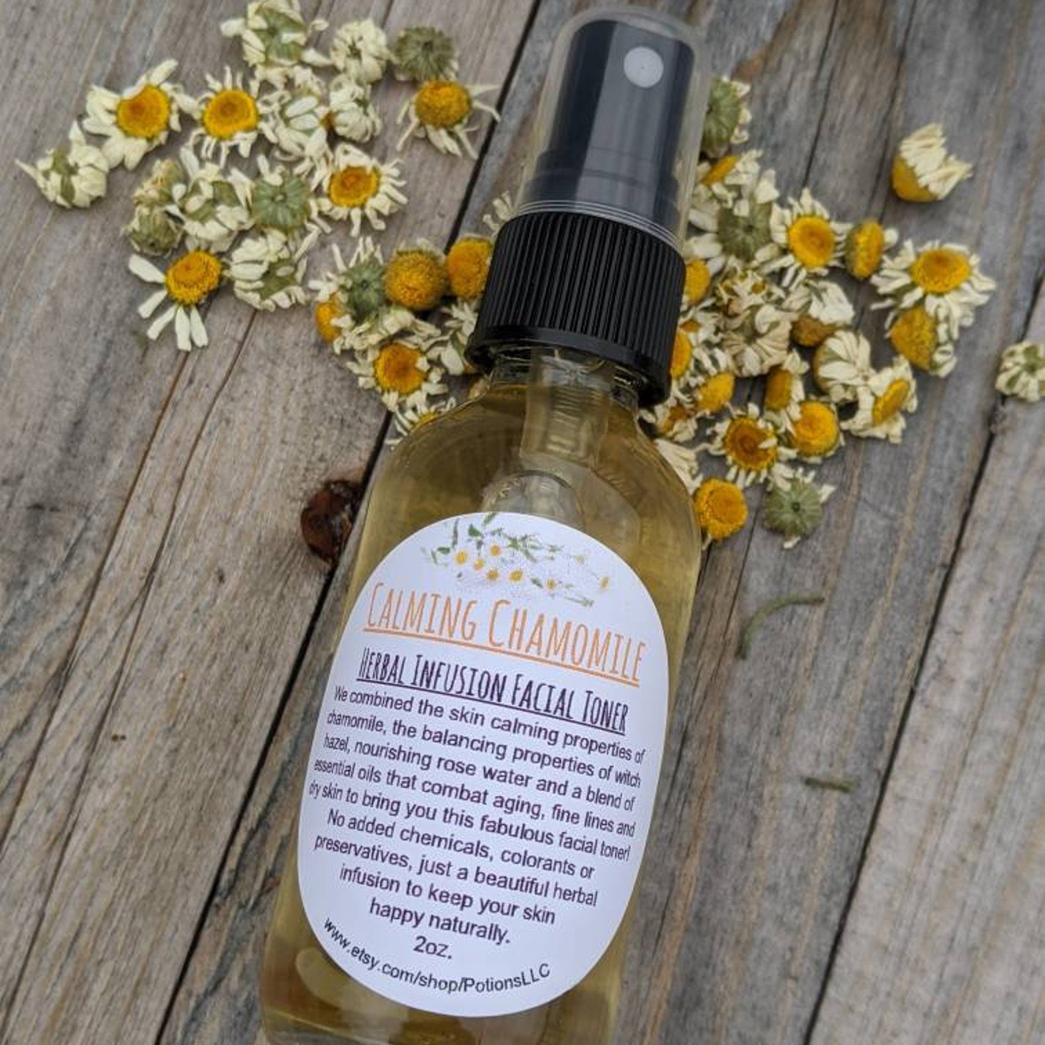 Facial toner bottle with black cap, yellow liquid, and chamomile flowers on wood surface
