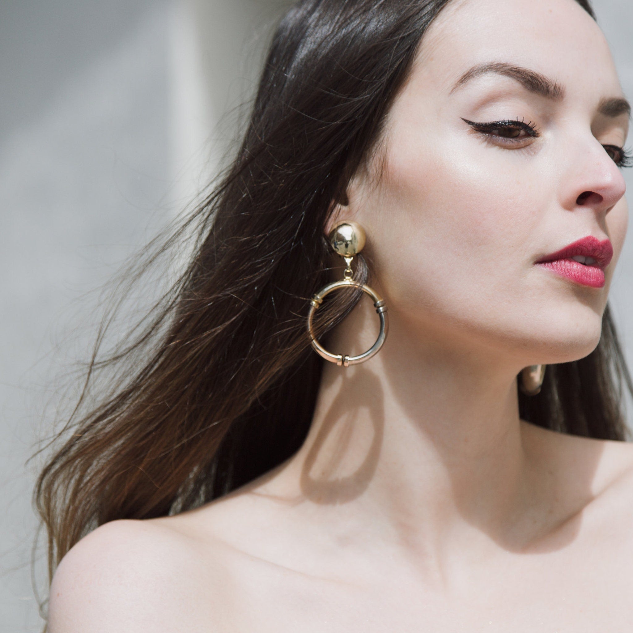 Gold hoop earrings with gold and silver accents, worn by woman with red lipstick