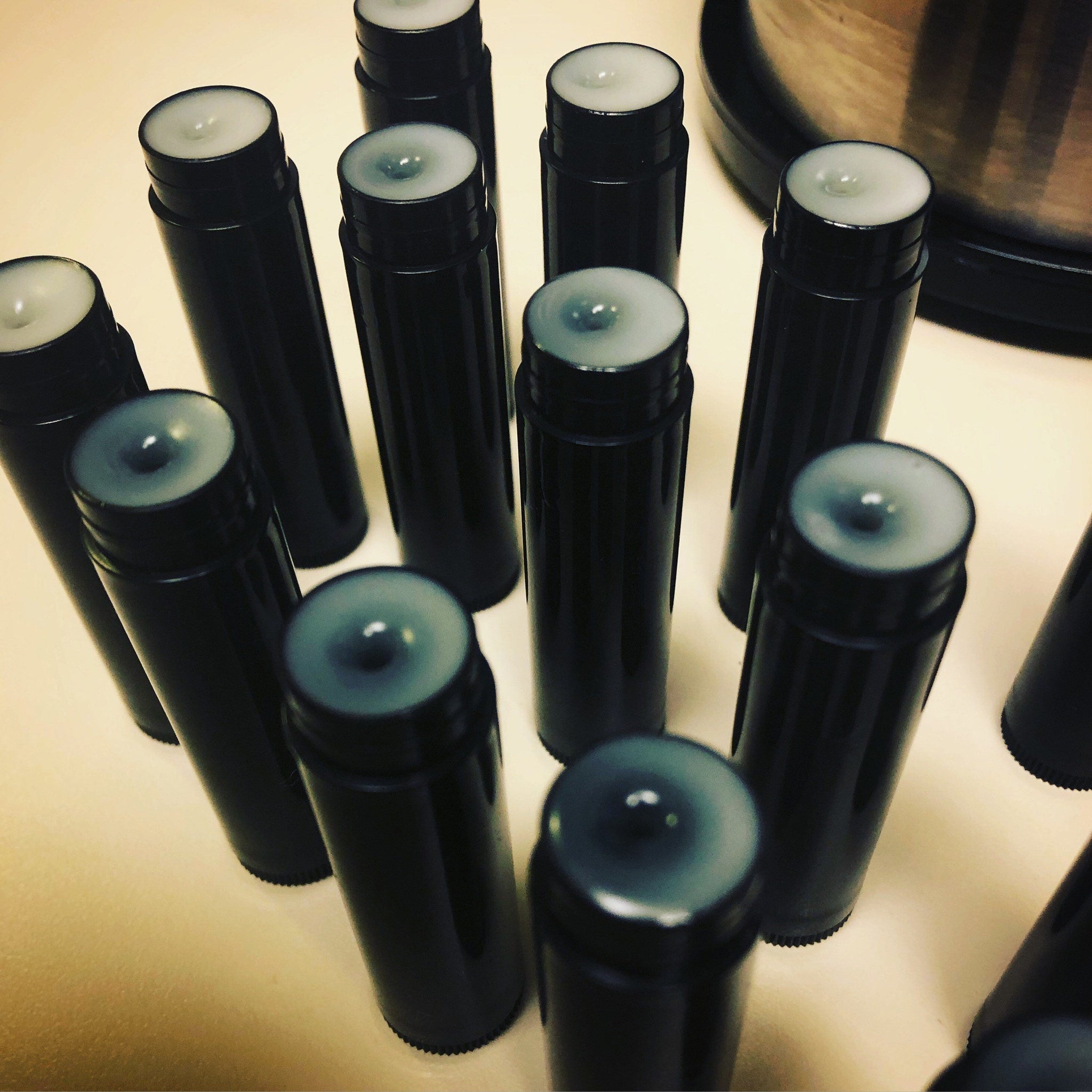 Lip balm tubes, black plastic tubes with white balm, arranged on a light surface