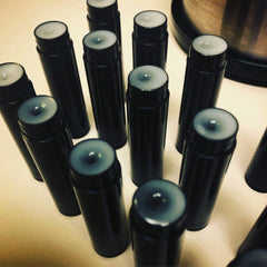 Lip balm tubes, black plastic tubes with white balm, arranged on a light surface